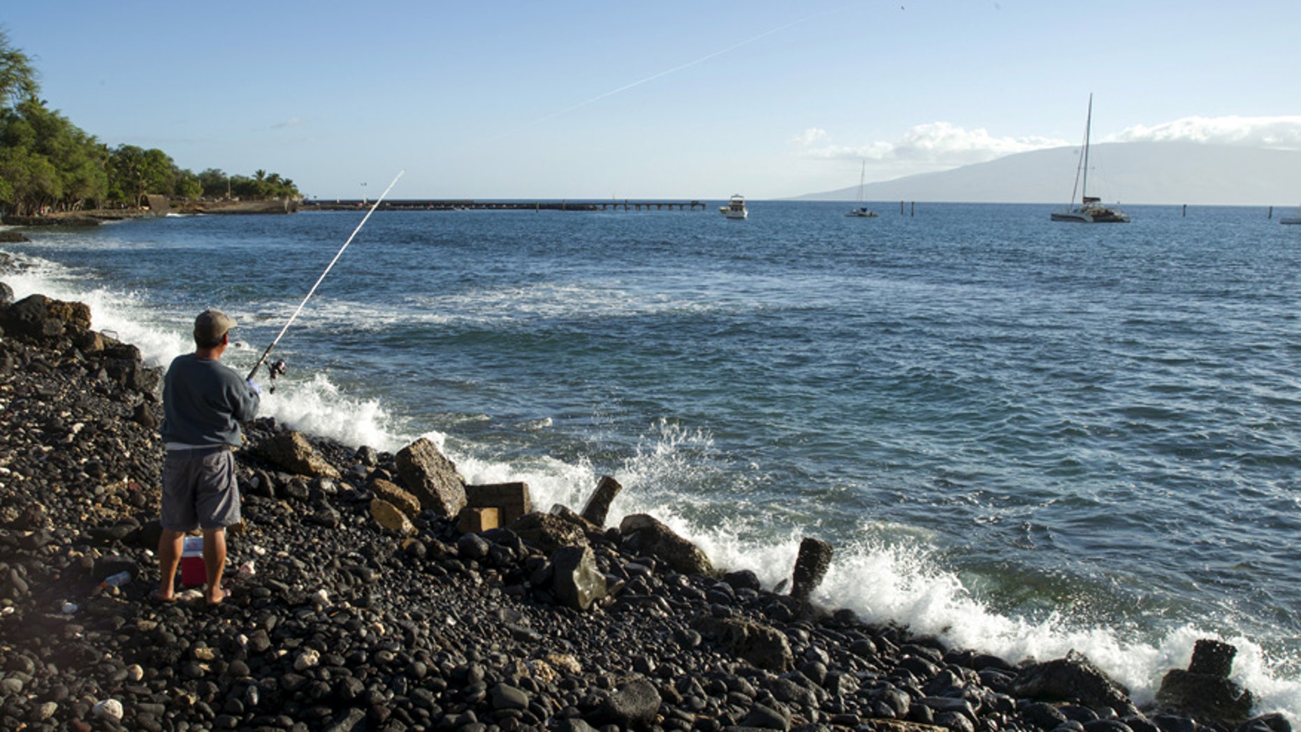 A fisherman casts his reel in waters off the coast of Maui, Hawaii.