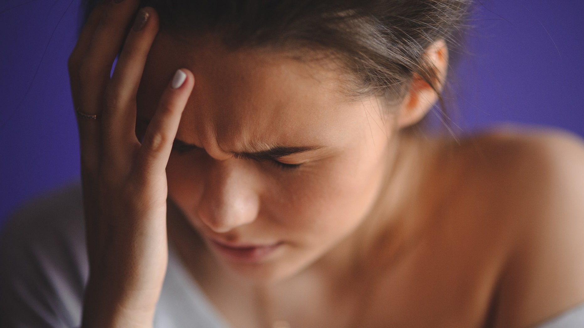 Teen woman with headache holding her hand to the head