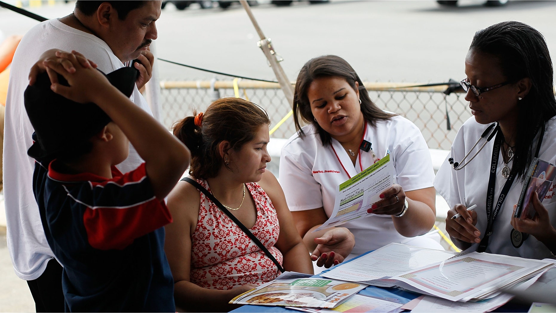 NEW YORK - JULY 20: Edwidge Lafortune of New York Presbyterian Hospital (R, with paper) gives information on nutrition to workers and their families during a free health-screening clinic for New York bodega convenience store workers July 20, 2010 in the Bronx borough of New York. Nurses and technicians from provided the free medical checks for the primarily-Hispanic bodega worker community, many of whom lack health insurance or regular medical care. (Photo by Chris Hondros/Getty Images)