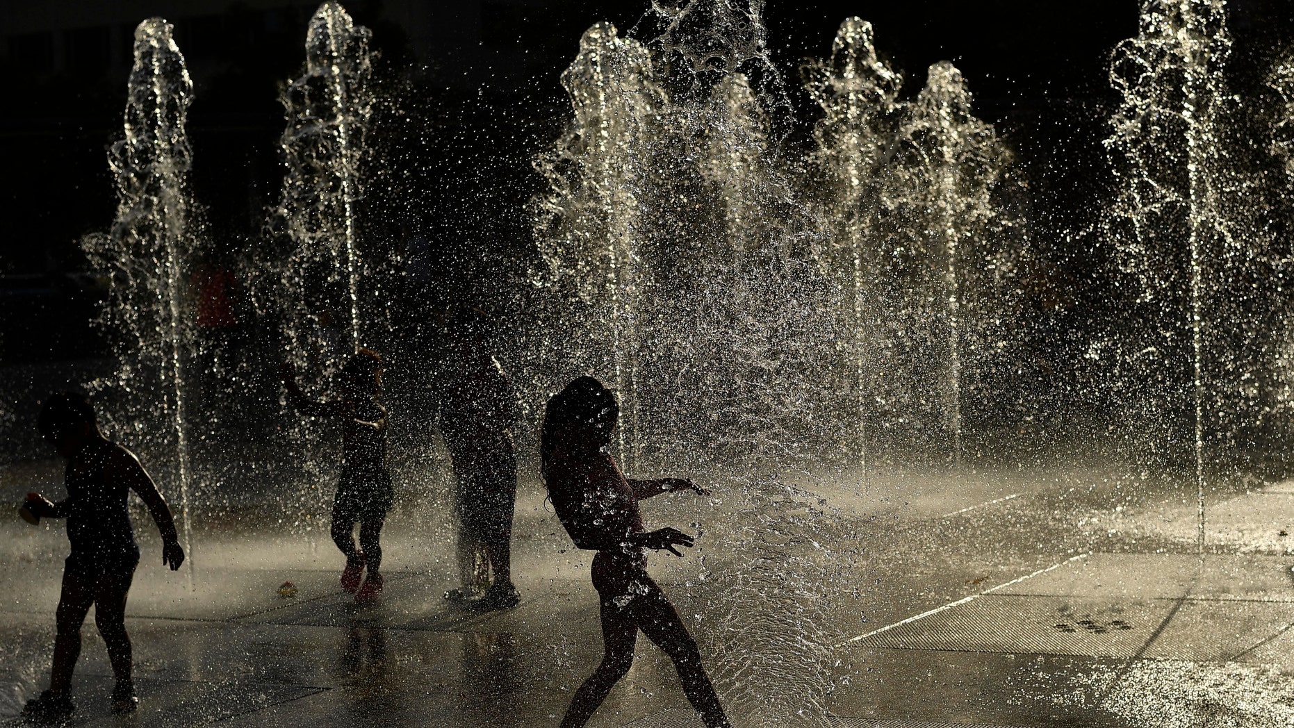 FILE - In this June 8, 2016, file photo, children cool off under water fountains on a sunny day, in Pamplona northern Spain. (AP Photo/Alvaro Barrientos, File)