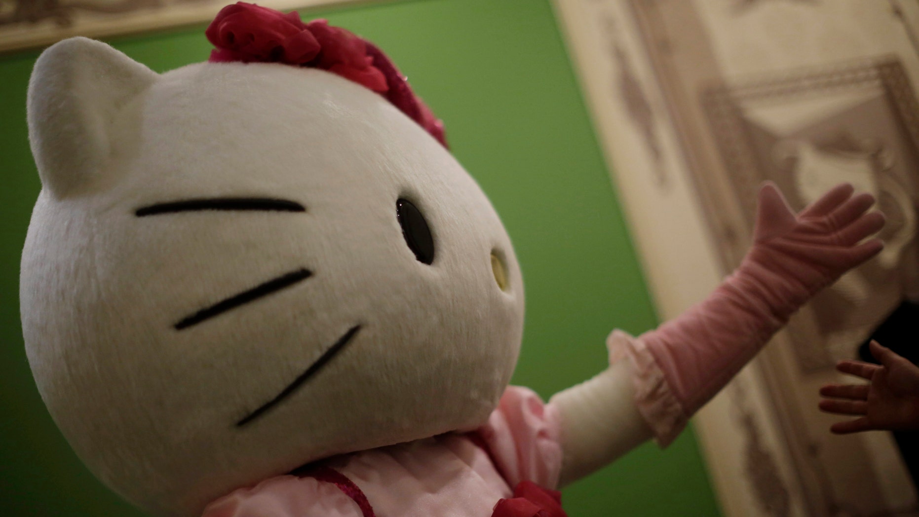 Oct. 30, 2014. A model dressing as Japanese character Hello Kitty greets a guest arriving to take a souvenir photo with her at Sanrio Puroland, a theme park featuring Hello Kitty in Tokyo.