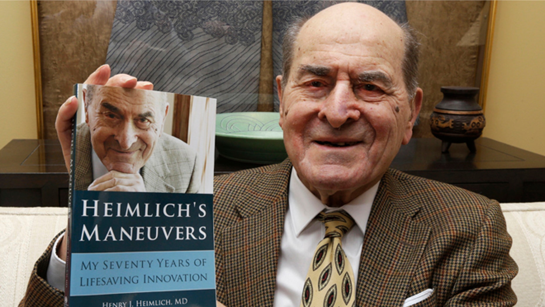 Dr. Henry Heimlich holds his memoir in 2014 photo.