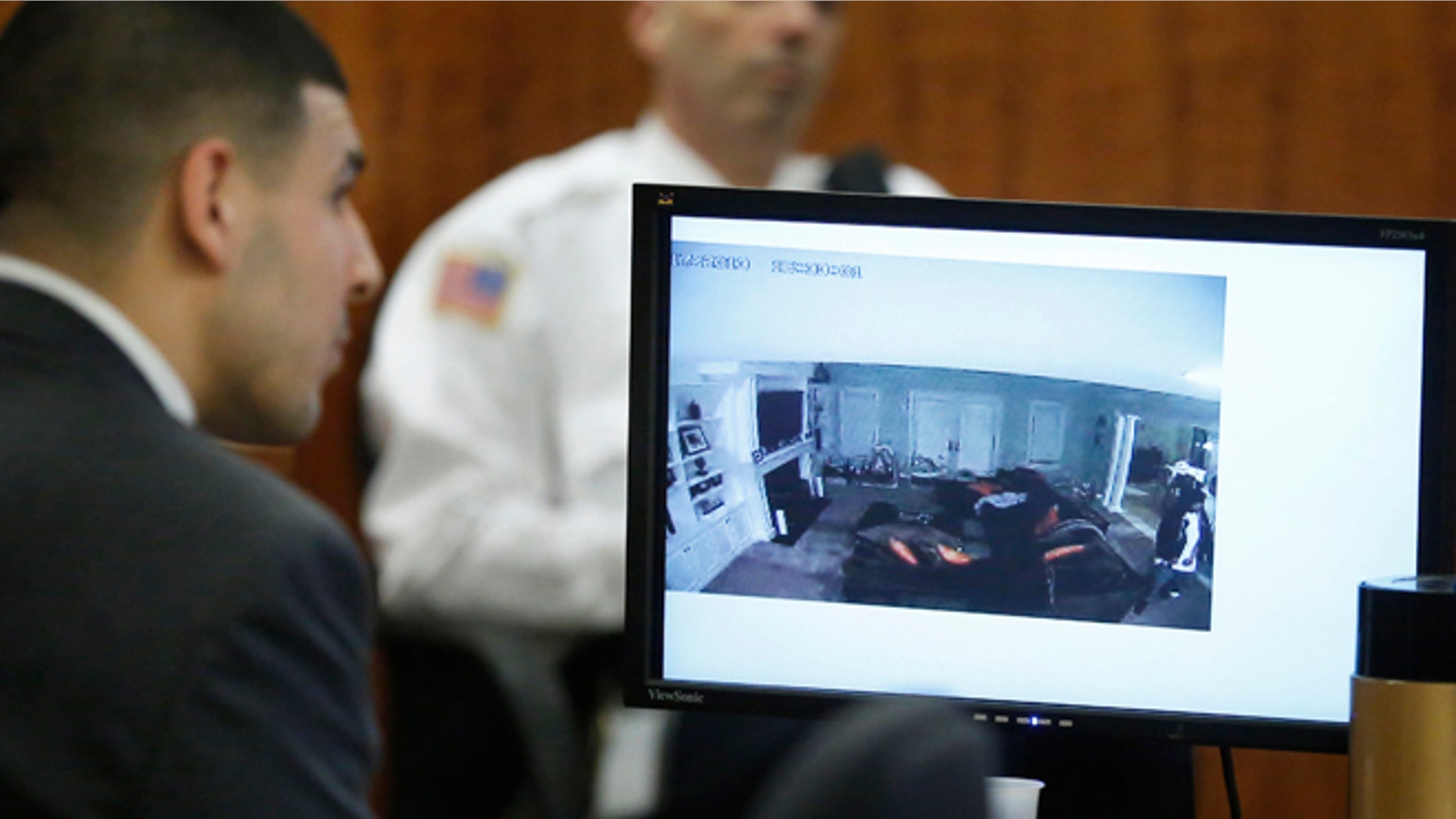 March 12, 2015: Former New England Patriots football player Aaron Hernandez, left, watches as a still frame from surveilance video is displayed on a monitor during his murder trial.