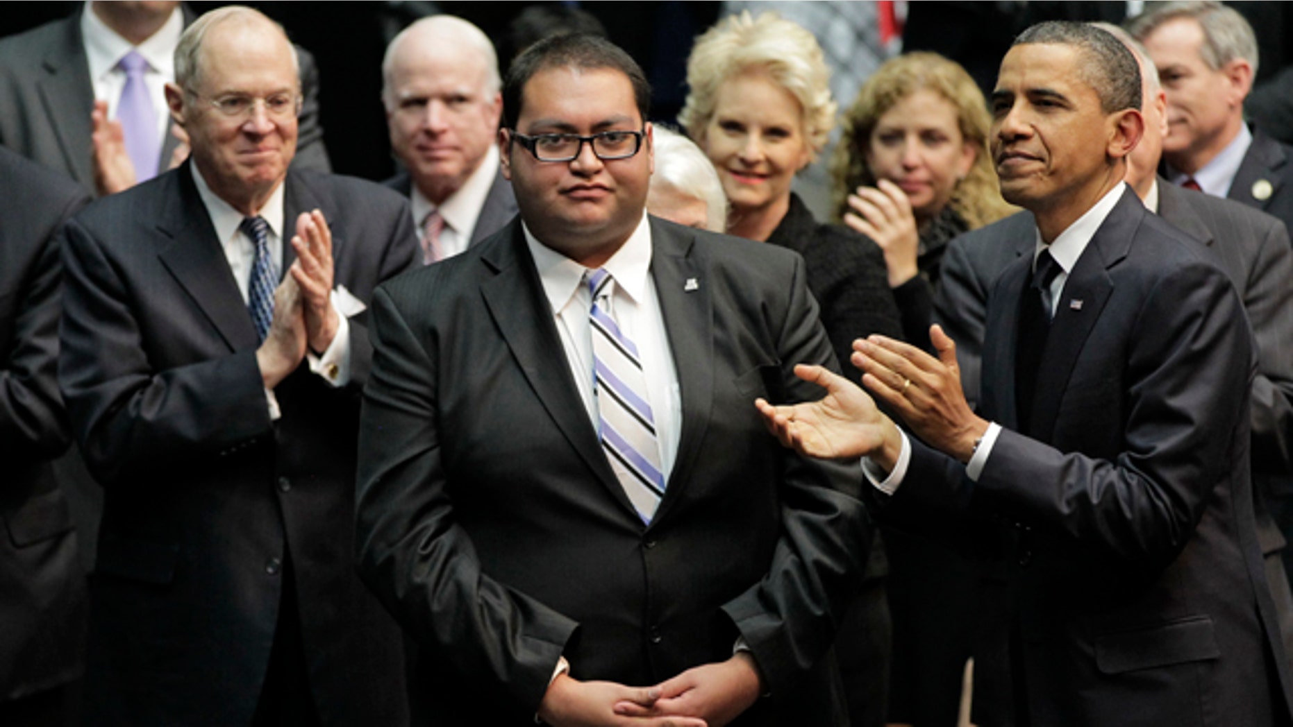 In this Jan. 12, 2011 file photo, Daniel Hernandez Jr., center, who was with Rep. Gabrielle Giffords when she was shot, receives a standing ovation during President Obama's visit to speak in Tucson, Ariz., in the wake of the mass shooting.