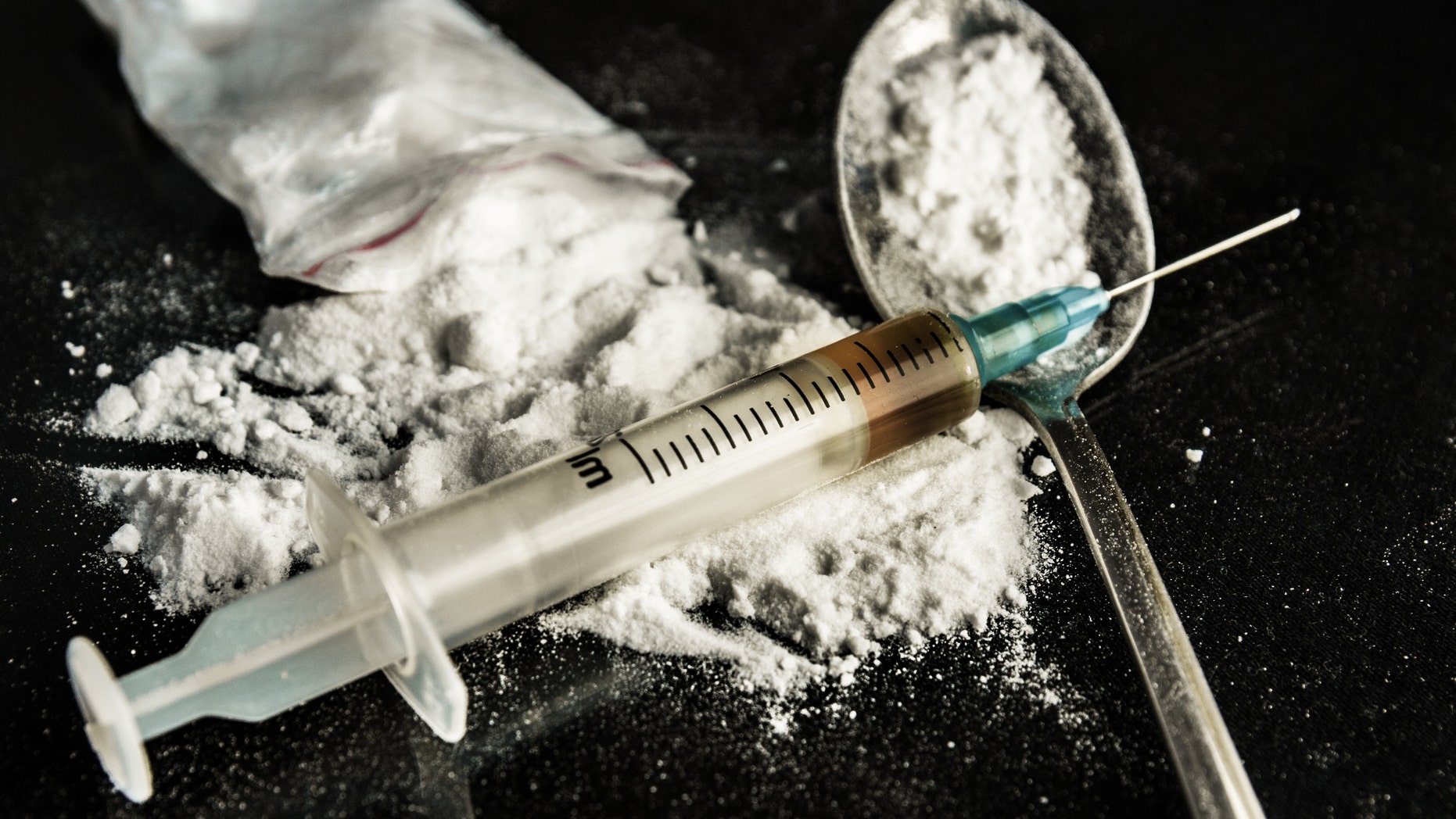 Drug syringe and cooked heroin on spoon