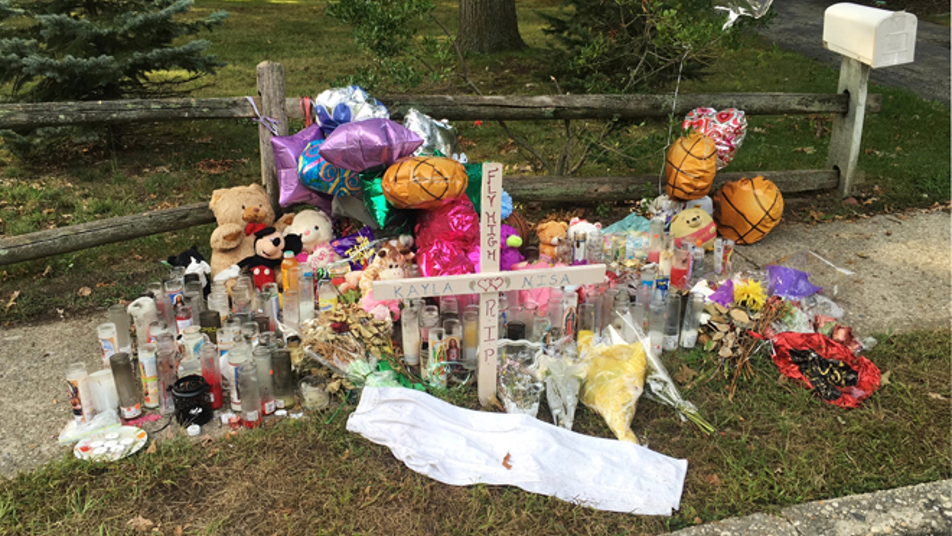 In this Sept. 27, 2016 photo, a memorial for Nisa Mickens and Kayla Cueva is located near the locations where their bodies were found in Brentwood, N.Y. The girls, who were best friends, were found murdered. Multiple teenagers from the same Long Island high school have been found dead and while police suspect all the deaths are related to gang violence, they are releasing few details.