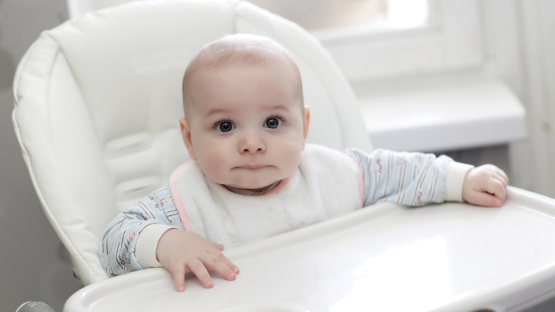 The serious baby sitting in highchair at home