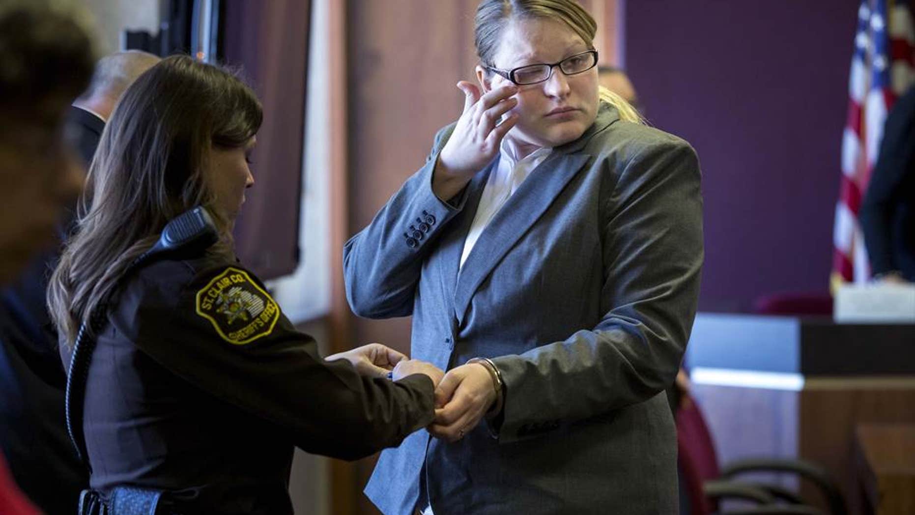 Hilery Maison wipes away a tear as she is handcuffed.