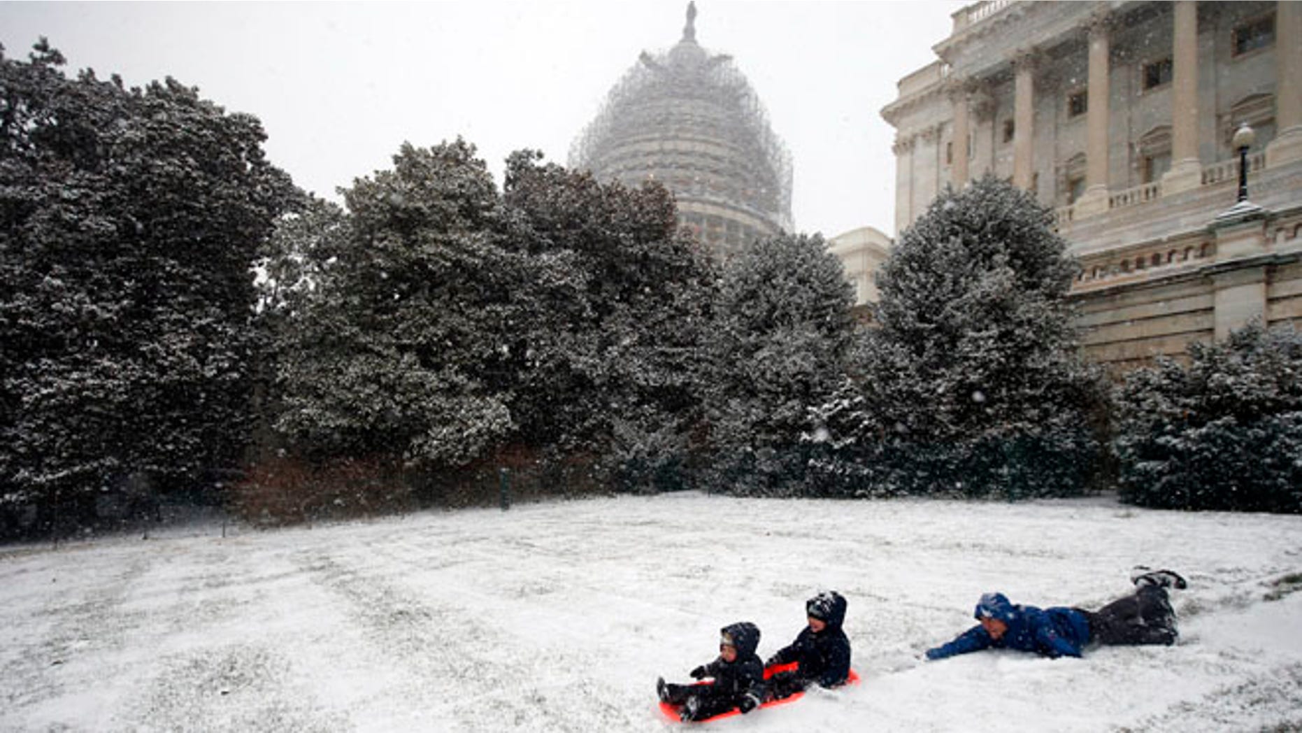 Friday, Jan. 22, 2016: Ben Cichy and his son Adrian, 18 months, and Logan 3, sled in the snow on Capitol Hill, in Washington, D.C. (AP)