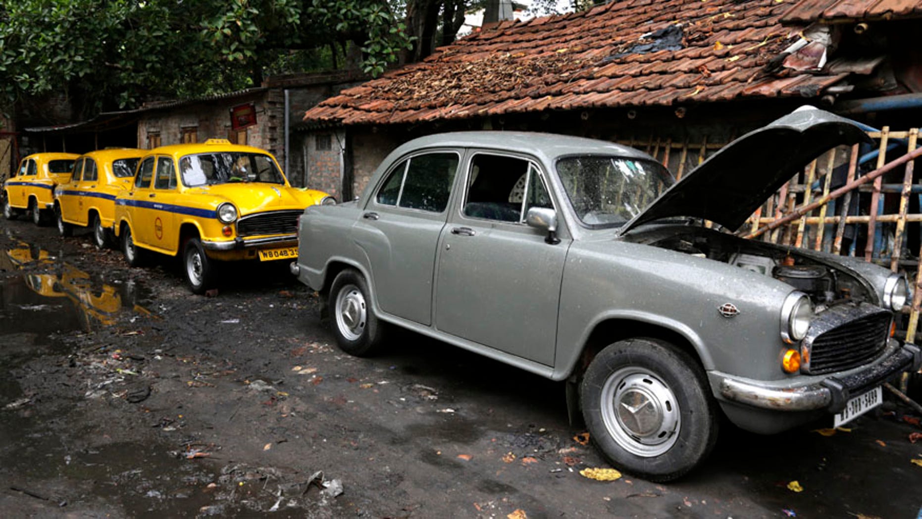 Ambassador cars, both taxis, in yellow and one private, are parked near a workshop for repairs in Kolkata, india, Monday, May 26, 2014. India's oldest car factory has abruptly suspended production of the hulking Ambassador sedan that has a nearly seven-decade history as the car of the Indian elite. (AP Photo/ Bikas Das)