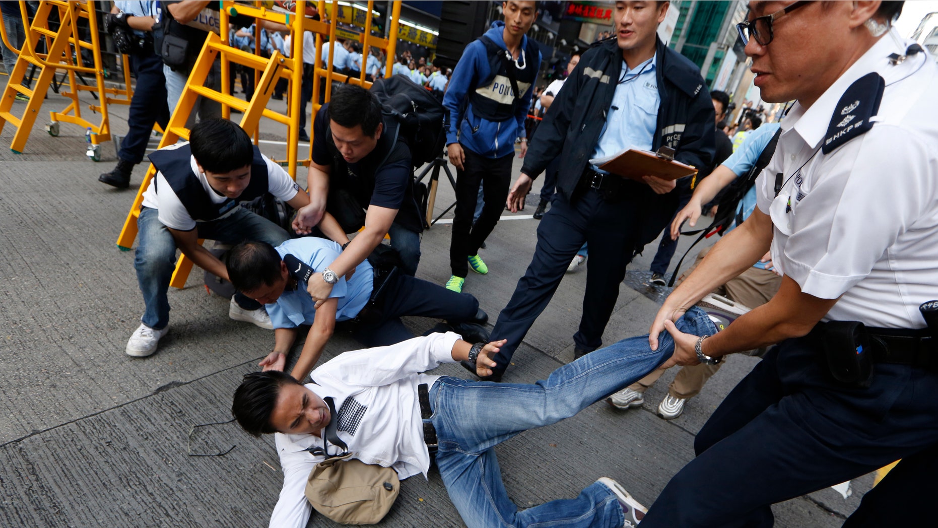 Nov. 25, 2014: A man is taken away by police officers as workers start clearing away barricades at an occupied area in Mong Kok district of Hong Kong
