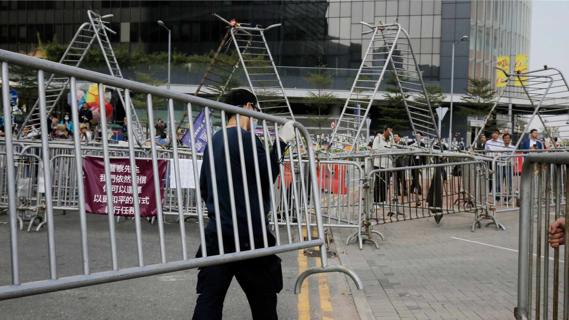Nov. 18, 2014: A pro-democracy protester removes barricades from an occupied area outside government headquarters in Hong Kong's Admiralty district