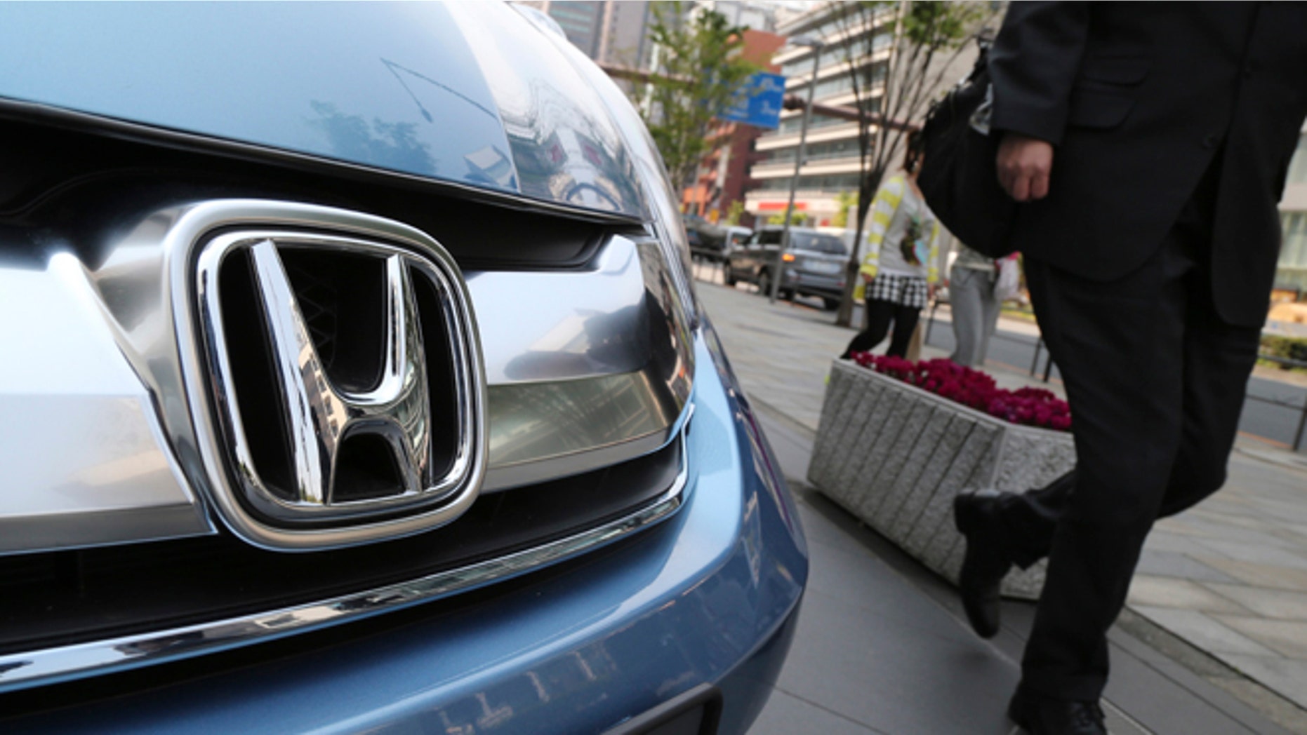 In this April 25, 2014 file photo, a man walks past a Honda on display at Honda Motor Co. headquarters in Tokyo.