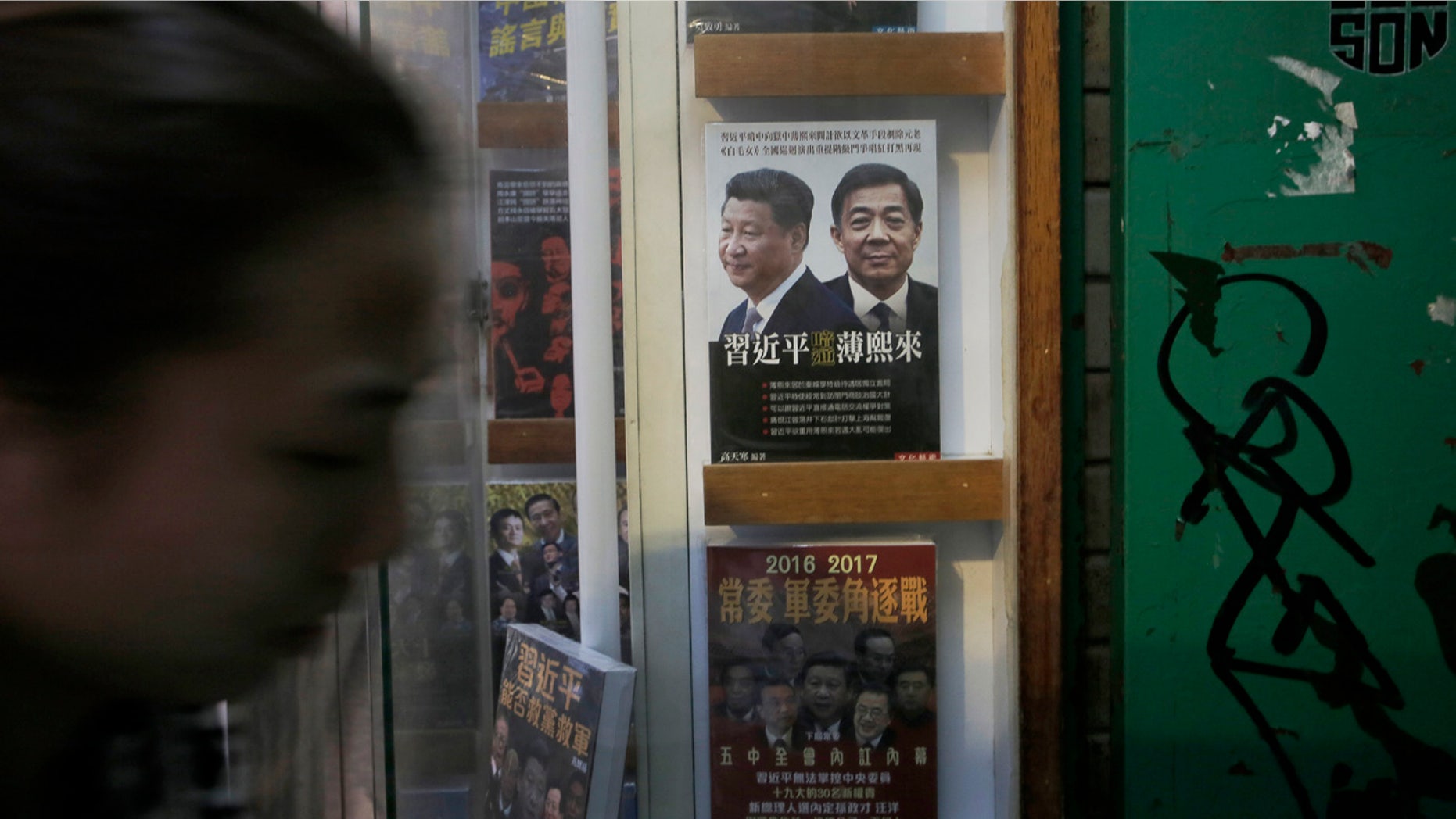 Jan 3. 2016: A woman walks past a book featuring a photo of Chinese President Xi Jinping, left, and former Politburo member and Chongqing city party leader Bo Xilai on the cover, at the entrance of the closed Causeway Bay Bookstore. (AP Photo/Vincent Yu)