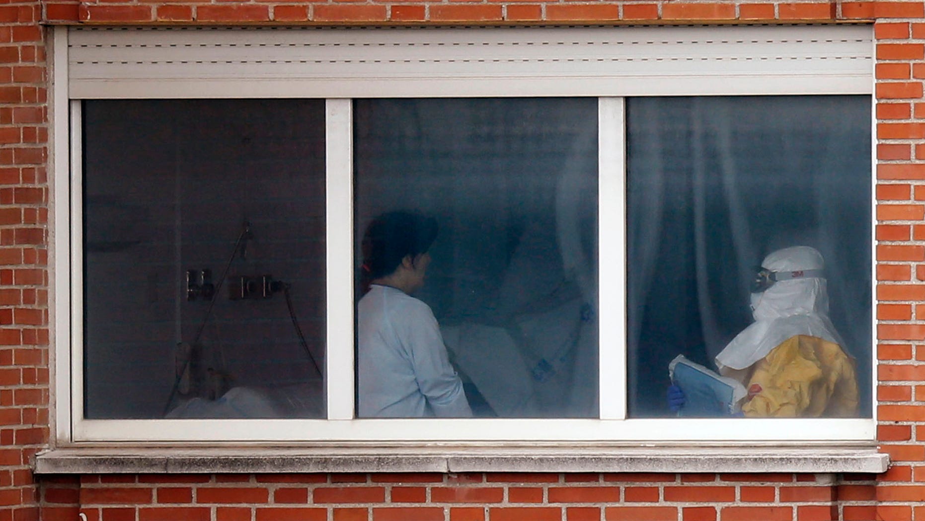 Oct. 9, 2014: A medical practitioner wearing protective clothing, right, stands next to an isolated patient on the sixth floor of the the Carlos III hospital in Madrid, Spain.
