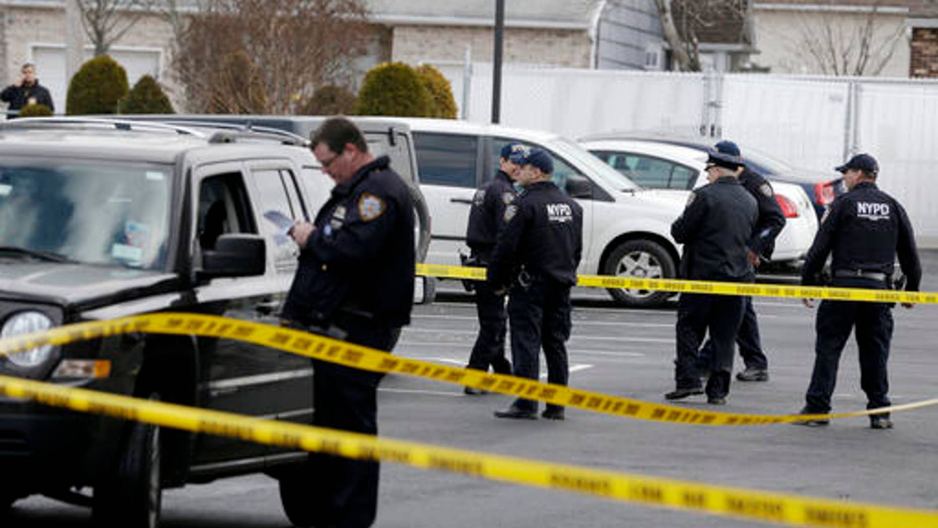 Police officers stand in the parking lot of a Ramada Inn, where authorities say a man stabbed a woman and her children in the Staten Island borough of New York, Wednesday, Feb. 10, 2016. (AP Photo/Seth Wenig)