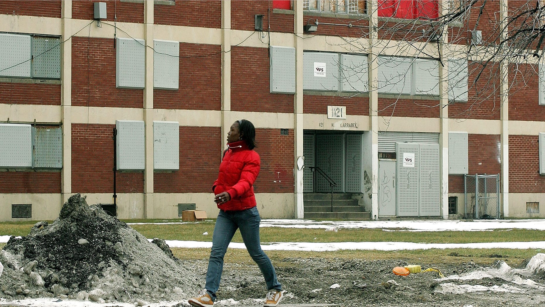 CHICAGO - JANUARY 12: Resident Oneisha Cannady walks past one of the few remaining Chicago Housing Authority Cabrini-Green public housing buildings January 12, 2005 in Chicago, Illinois. The run-down and dilapidated buildings sit on prime real-estate property that the city of Chicago wants to tear down and redevelop. At one time, the CHA's Cabrini-Green development had 22 high-rise buildings on 70 acres of land with 3,500 apartment units housing approximately 15,000 residents. (Photo by Tim Boyle/Getty Images)