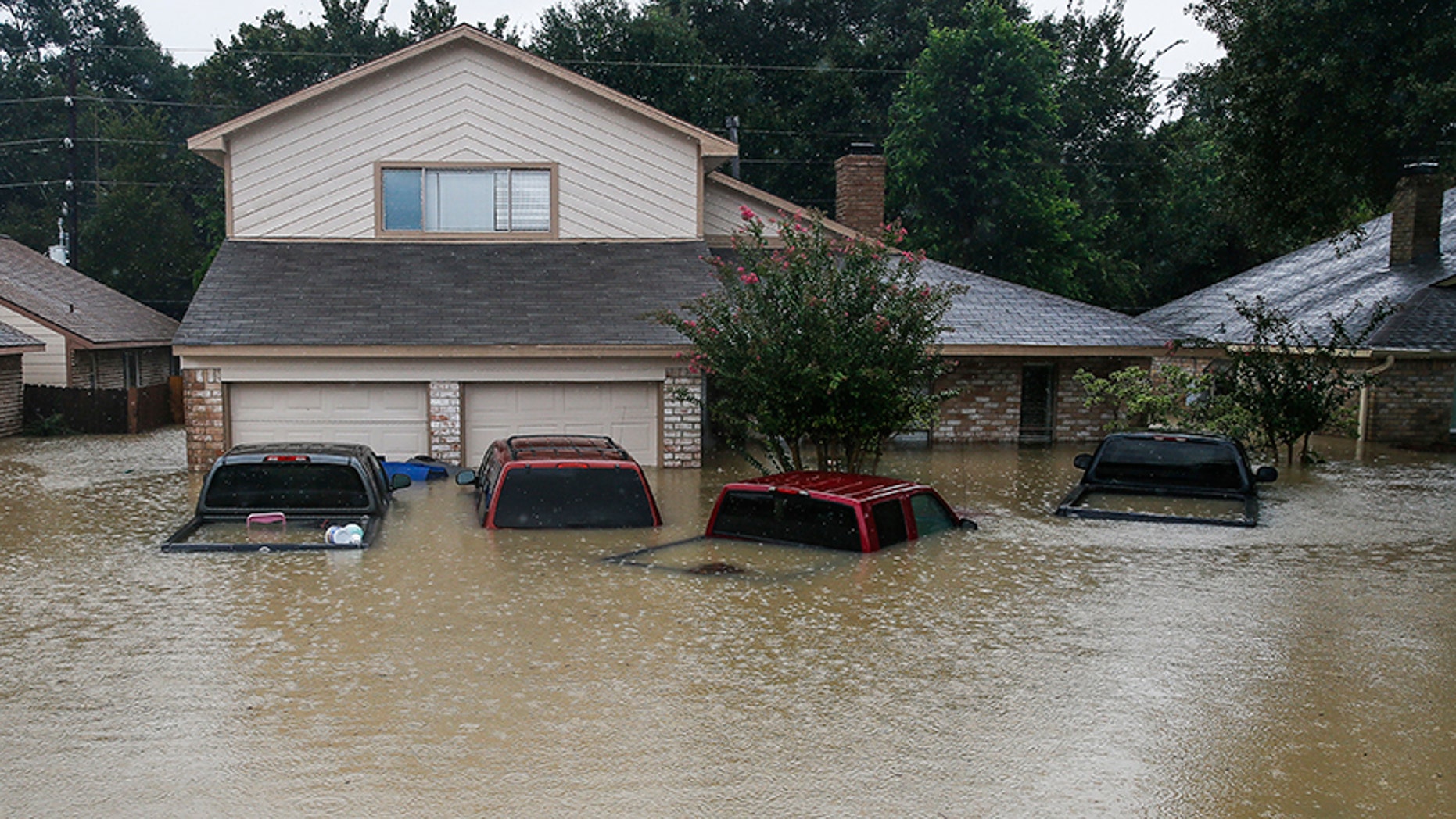 FILE - In this Aug. 29, 2017, file photo, trucks are submerged on Pine Cliff Drive in Houston during heavy rainfall from Tropical Storm Harvey. Few American cities depend on cars as much as Houston, and Harvey's record rainfall left flooded roads and neighborhoods with cars submerged and, in most cases, impossible to salvage. (Michael Ciaglo/Houston Chronicle via AP)