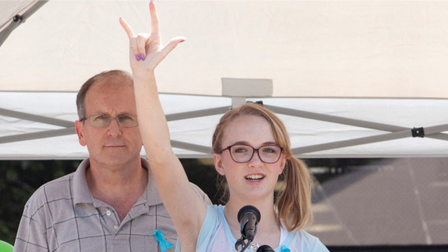 July 12, 2014: Cassidy Stay stands with her grandfather Roger Lyon (L) as she addresses the crowd during a memorial service for members of the Stay family who were murdered in their home Wednesday, in Spring, Texas.