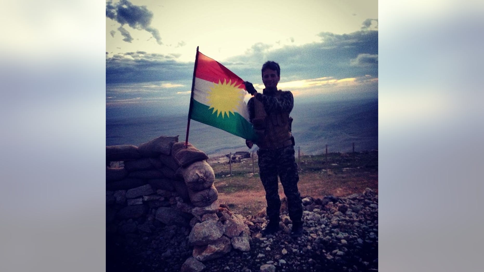 A Kurdish Peshmerga soldier holds the KRG flag on the frontlines of Mosul Dam.