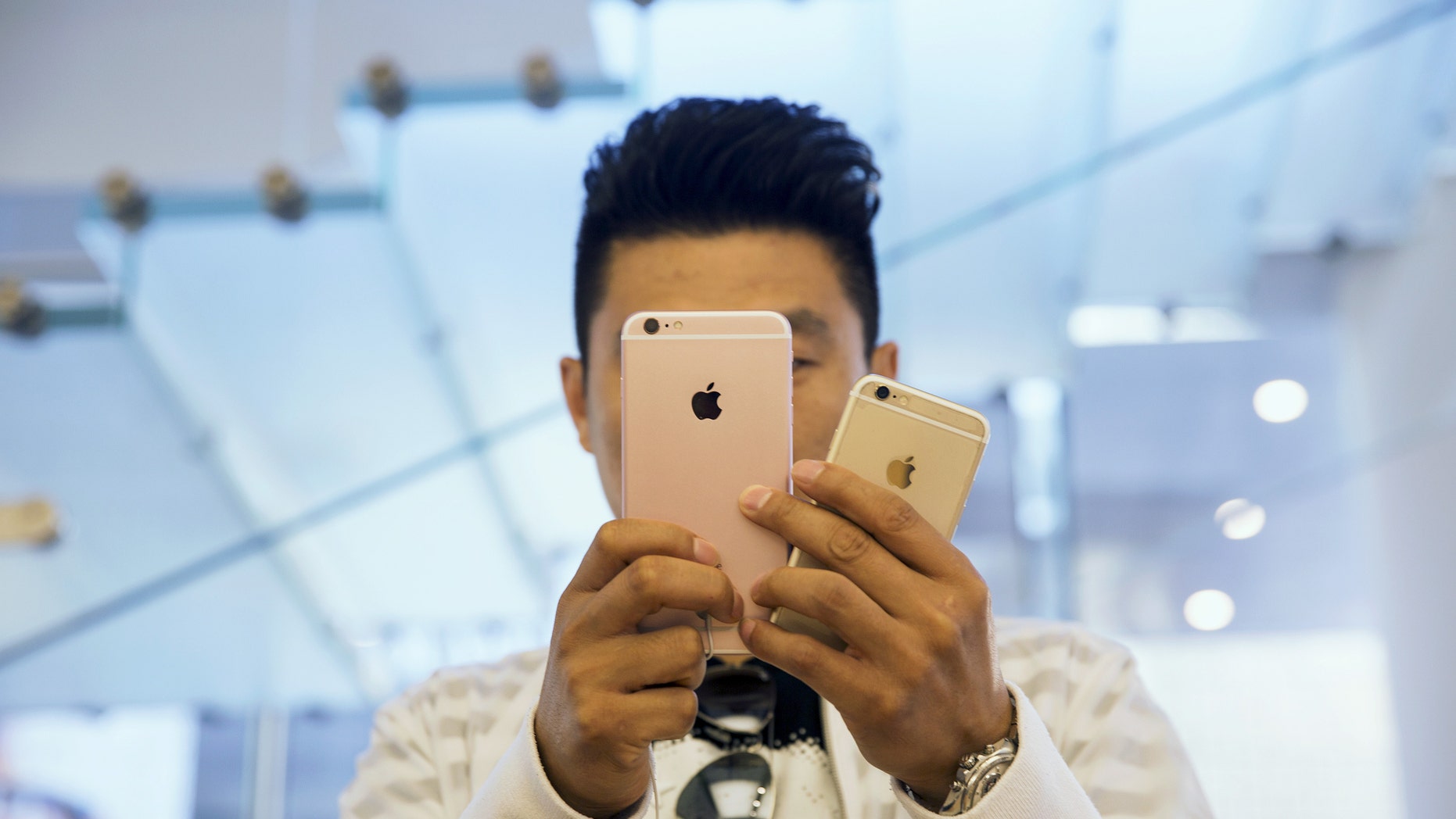 A man takes pictures as Apple iPhone 6s and 6s Plus go on sale at an Apple Store in Beijing, China Sept. 25, 2015.