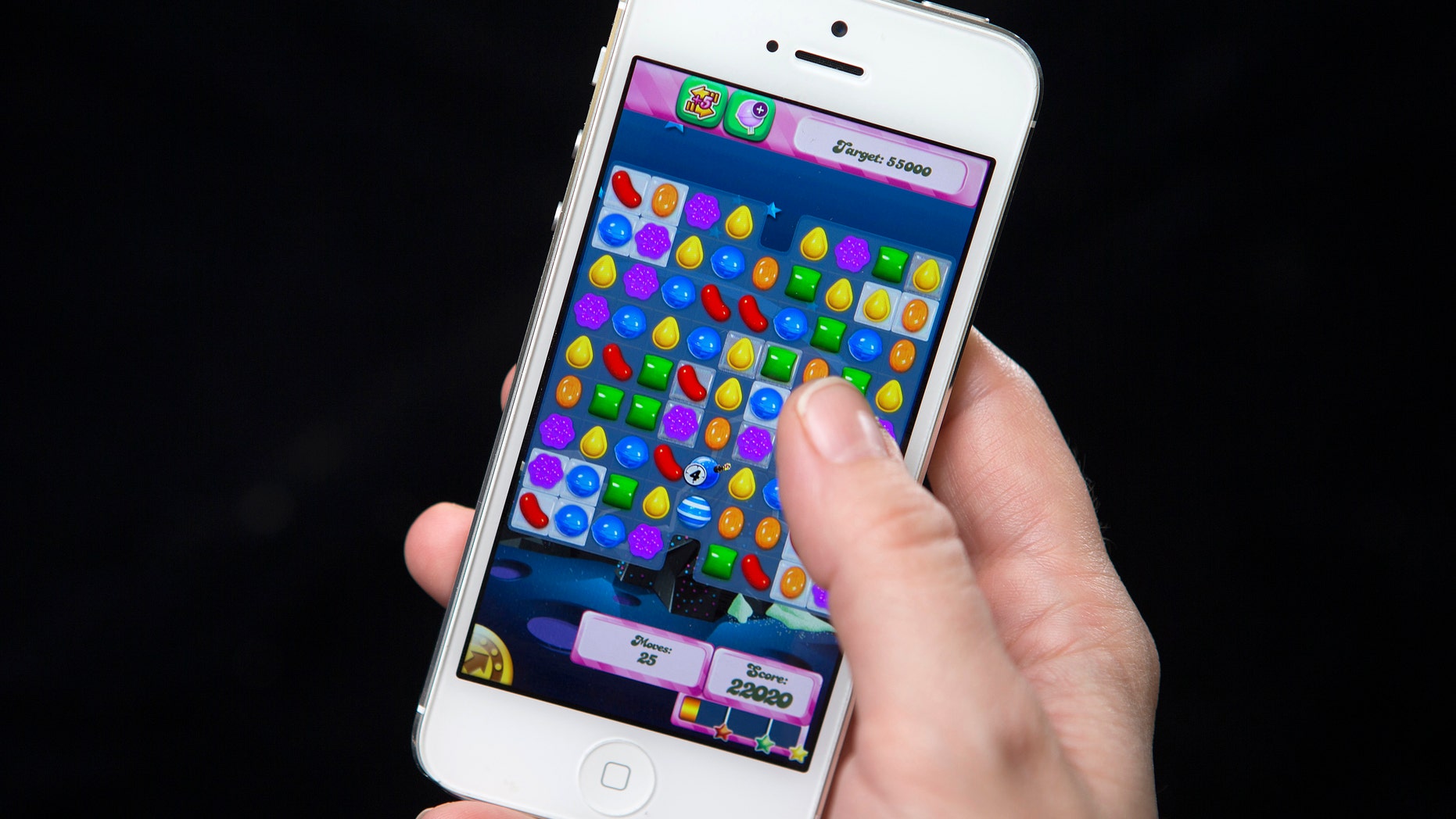 A woman poses for a photo illustration with an iPhone as she plays Candy Crush in New York February 18, 2014.