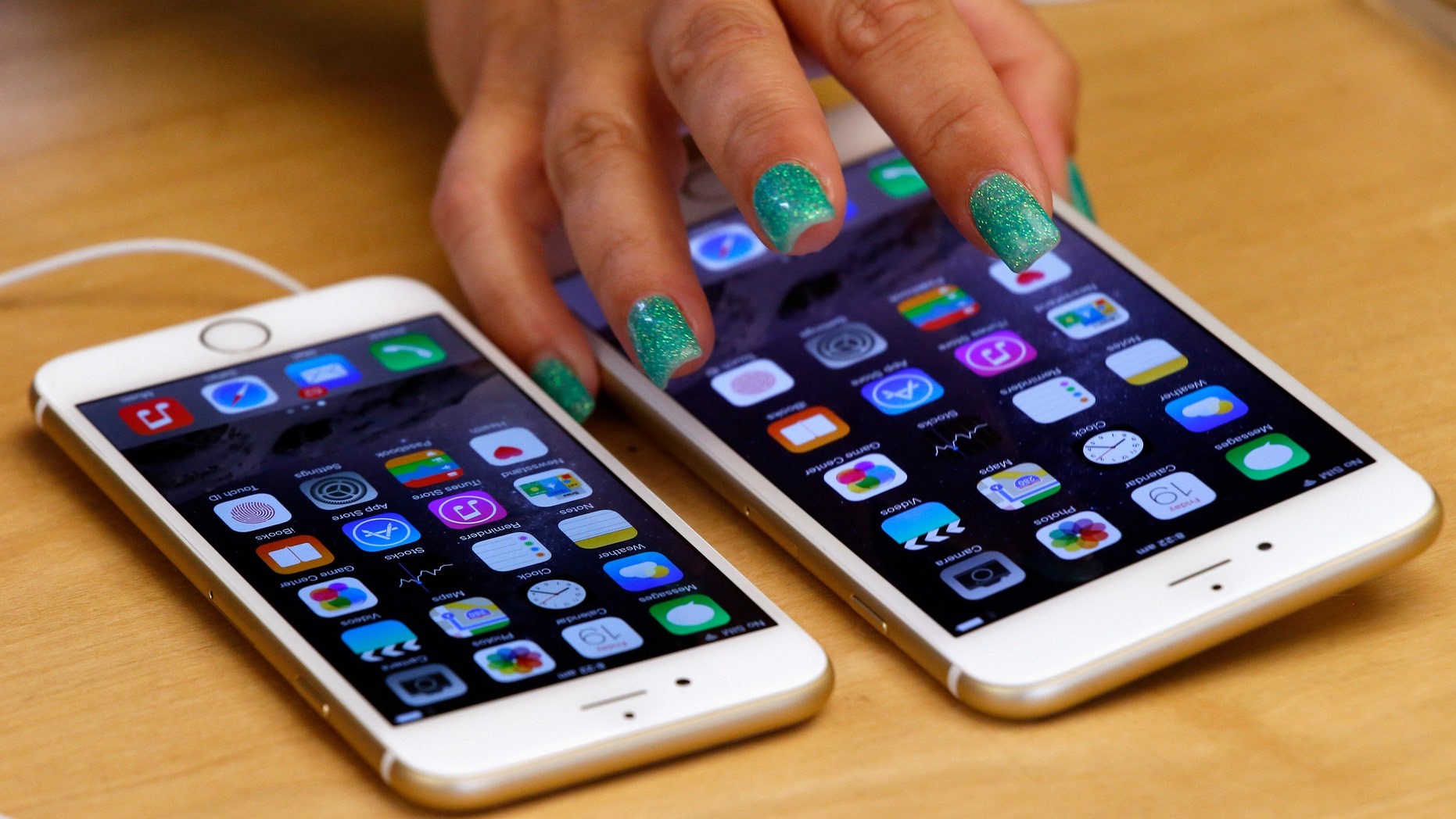 A woman touches an iPhone 6 Plus as it sits next to an iPhone 6 after they went on sale at the Apple store in Sydney.