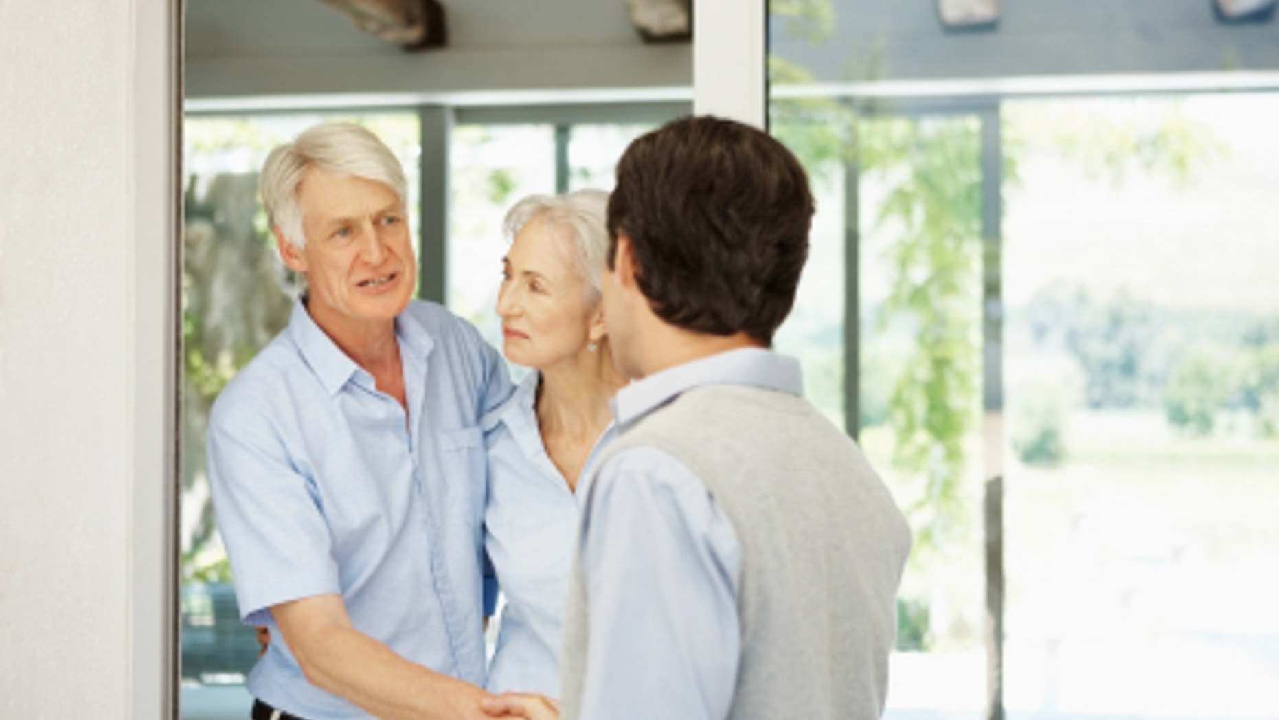 Successful elderly couple welcoming a guest at their house