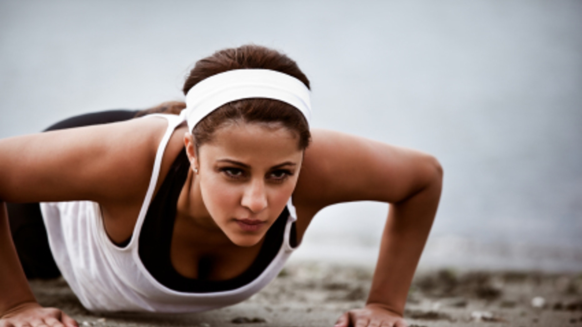 A beautiful asian woman doing push up at a beach