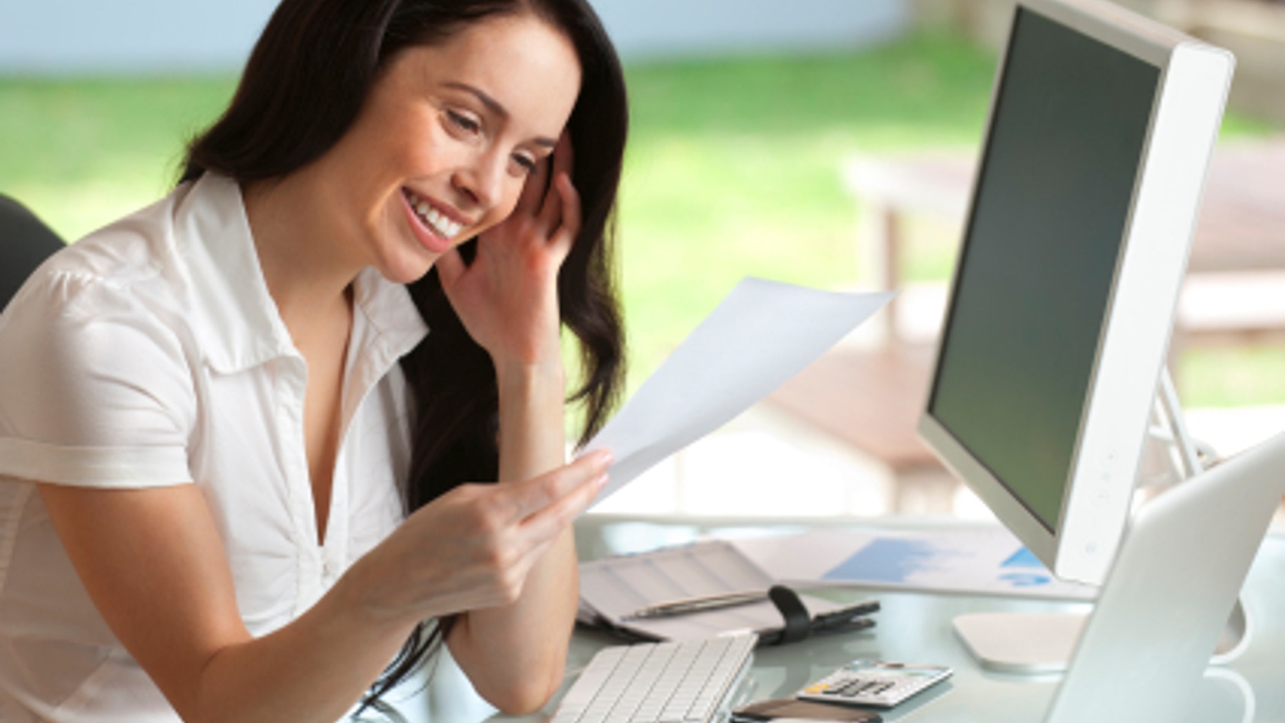 Attractive woman smiling reading a document at her desk