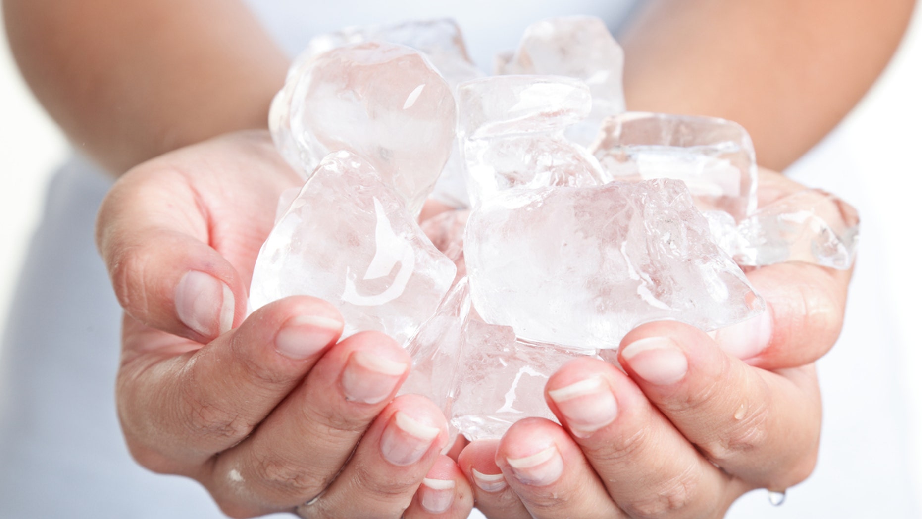 Ice cold hands. Woman hands holding ice cubes - closeup.