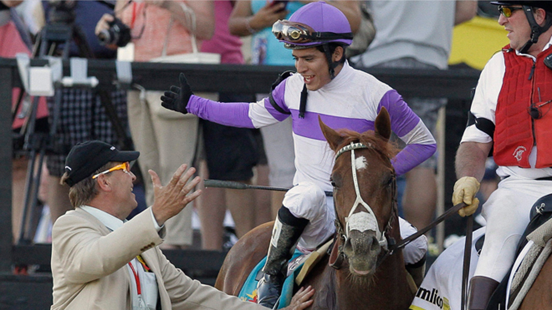 May 19, 2012: Jockey Mario Gutierrez, aboard I'll Have Another, is greeted by horse masseuse Larry "Thumper" Jones, left, while outrider Clark Casey looks on after winning the 137th Preakness Stakes horse race at Pimlico Race Course in Baltimore.