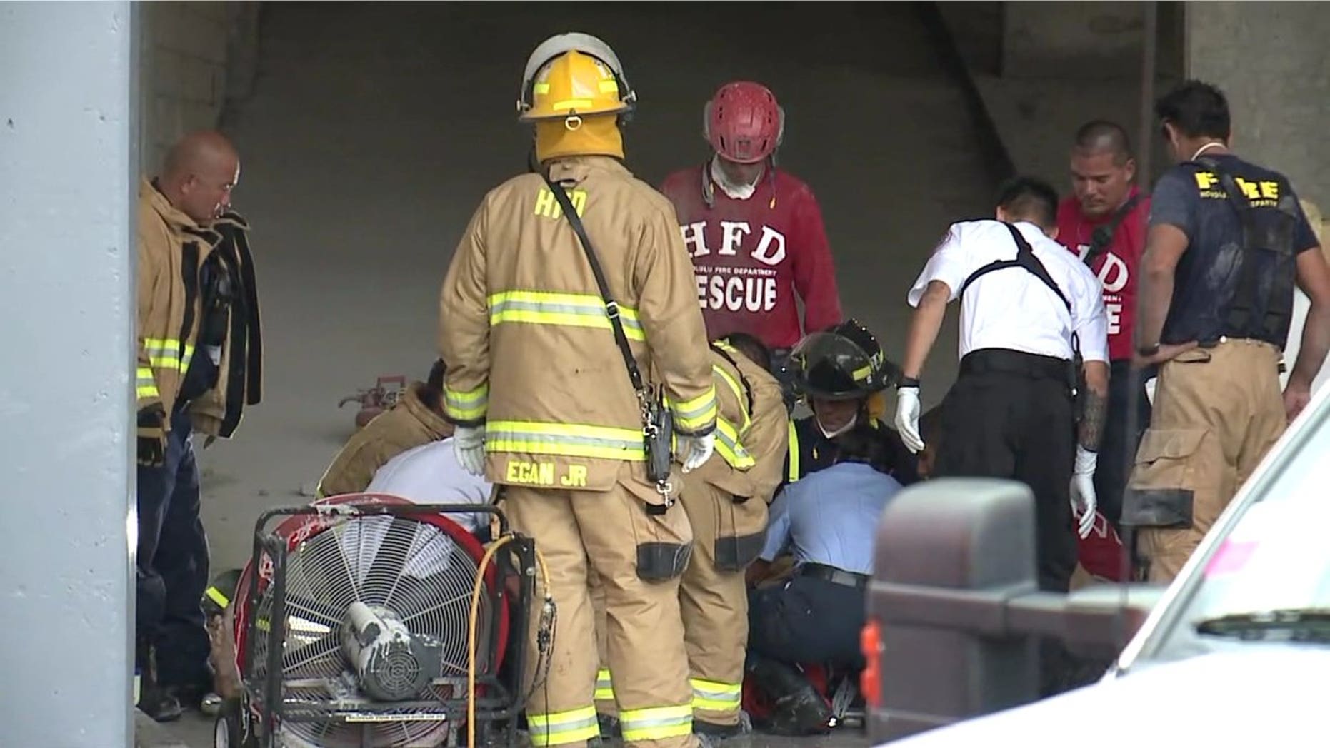 Emergency crews treat a man who was freed from between two buildings in Honolulu, March 23, 2018.