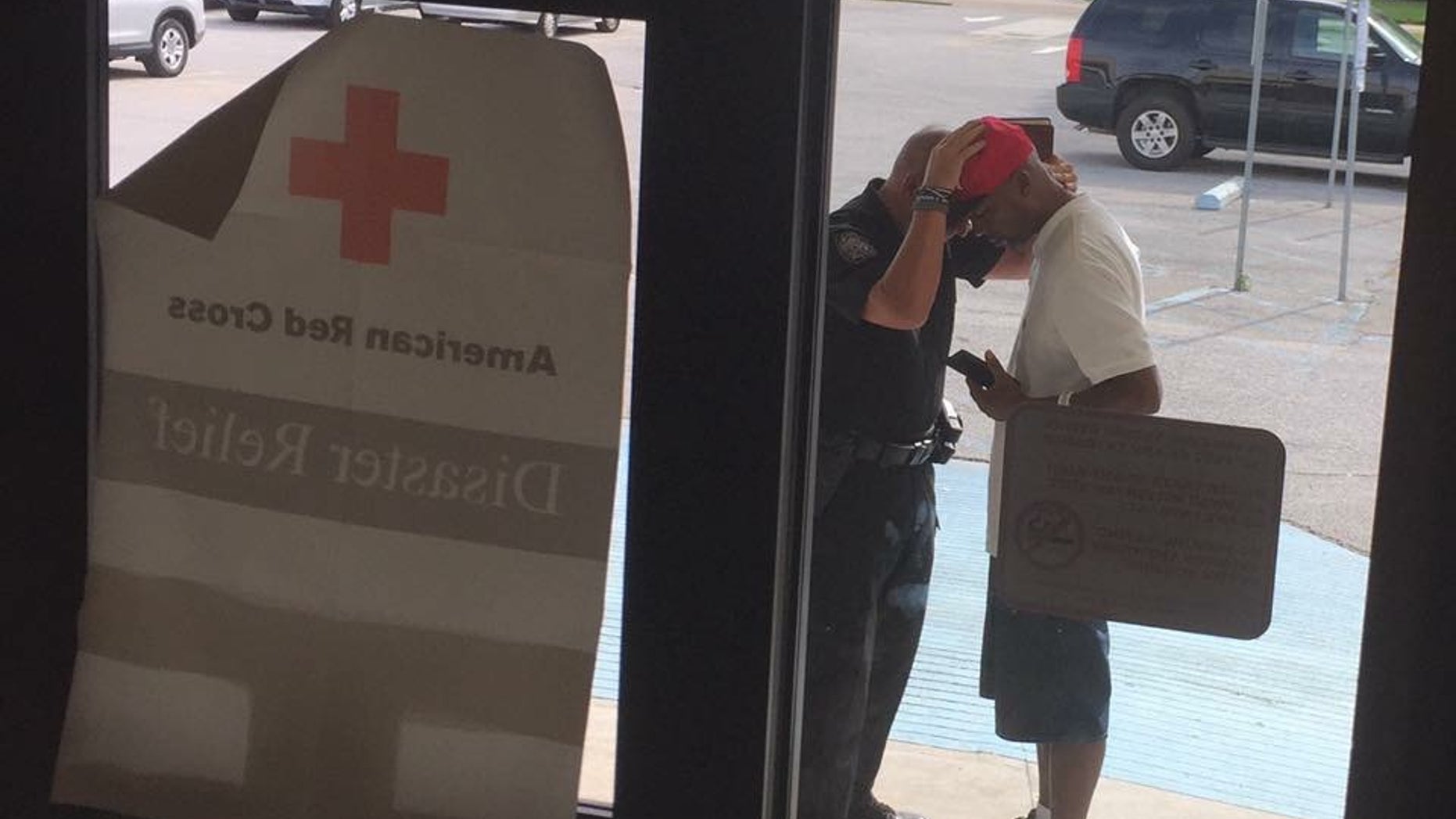 This photo was taken after the Red Cross told the police captain he could not pray inside the shelter. The man he is praying with lost his home in the flood.
