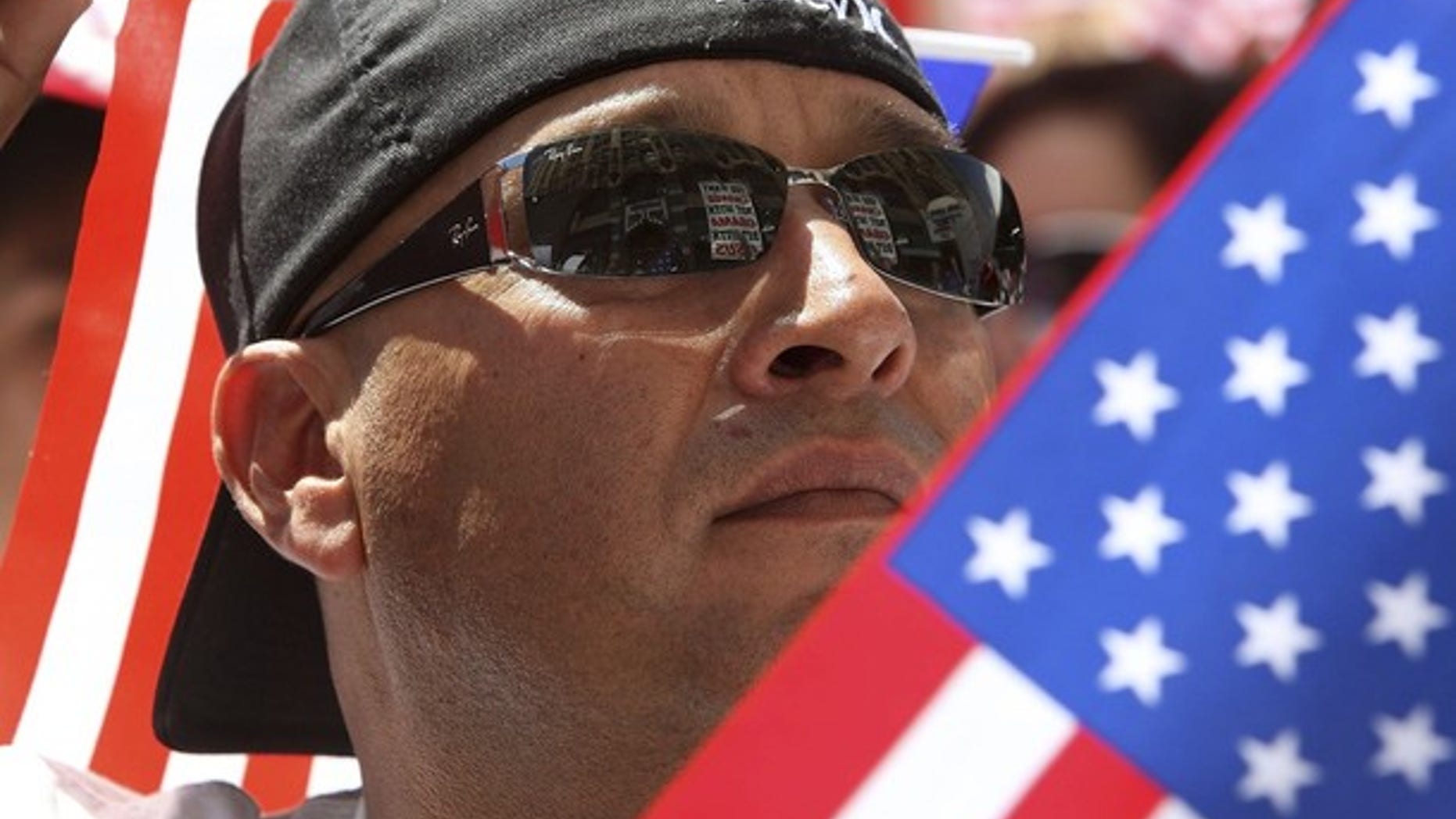 A man carrying U.S. flags joins thousands of protesters in a march up Broadway during a May Day immigration rally in Los Angeles, California, May 1, 2010. (Reuters)