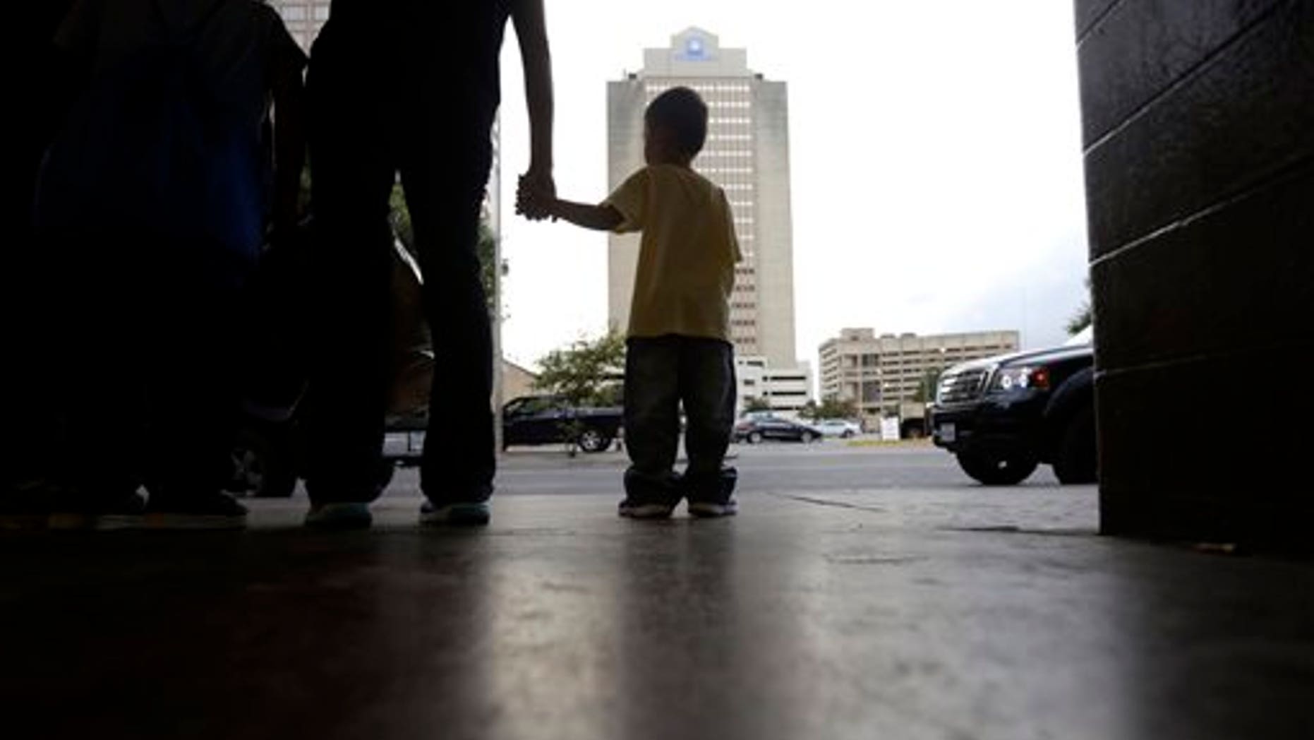 Tuesday, July 7, 2015, A young boy holds hands with his mother at a bus station after they were released from a family detention center in San Antonio, Texas.