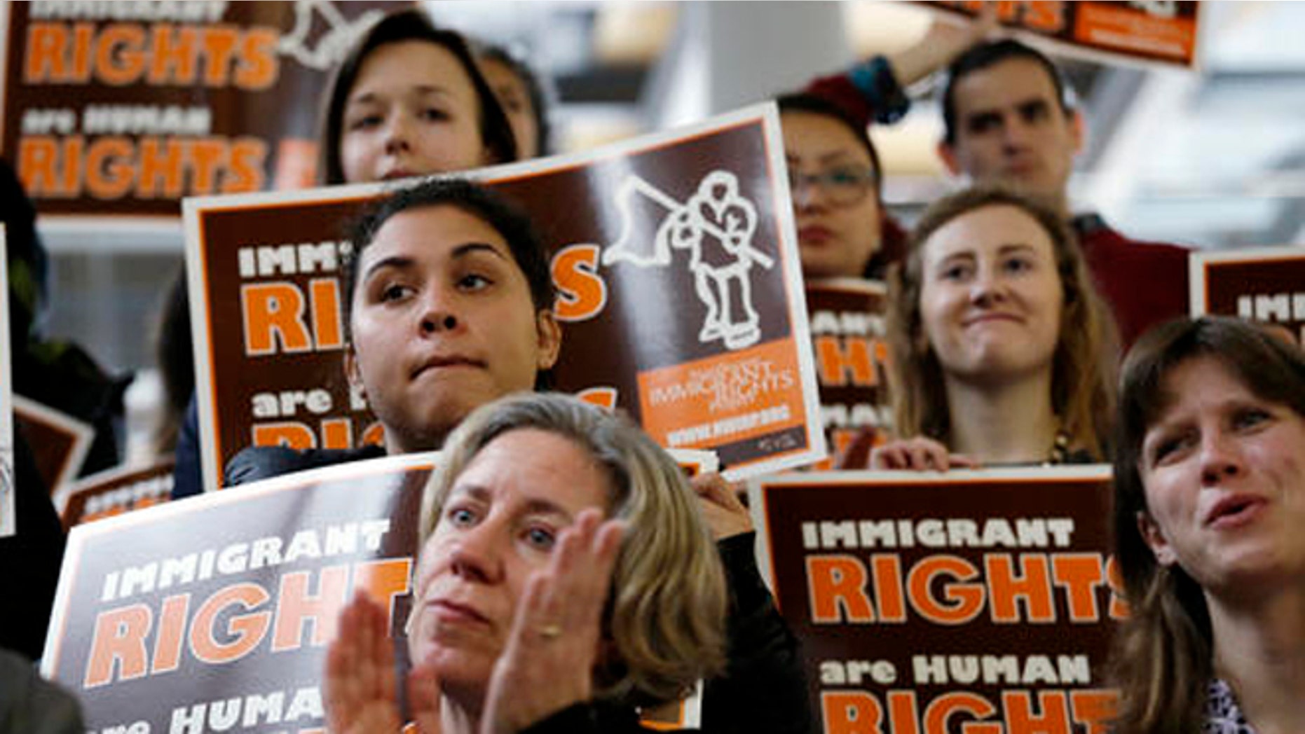 Demonstrators holding immigrant rights signs look on at a post-election event of elected officials and community leaders Wednesday, Nov. 9, 2016, at City Hall in Seattle. Seattle Mayor Ed Murray said the country had elected a leader who has "demonstrated outright misogyny" and displayed "racism and authoritarian tendencies." Murray said despite the views held by President-elect Donald Trump, Seattle would remain a welcoming city for immigrants, minorities and others. (AP Photo/Elaine Thompson)