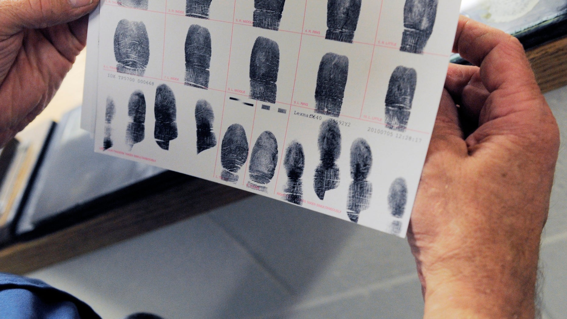 In this July 26, 2010 photo,Senior Deputy Jerry Anttila looks at a set of fingerprints for an unidentified suspect during the booking process at the Arapahoe County Justice Center in Centennial, Colo. (AP)