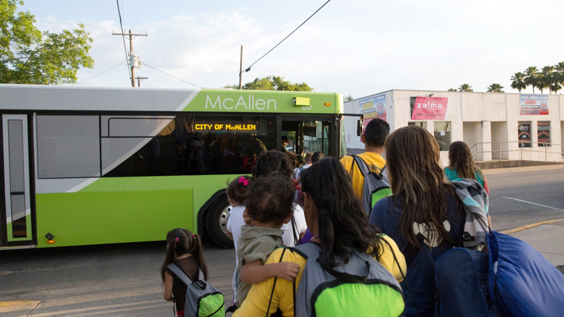 FILE - In this file photo from April 30, 2015, immigrant families, many of them mothers with children, board a bus headed to the downtown bus station in McAllen, Texas. (AP Photo/Seth Robbins, File)