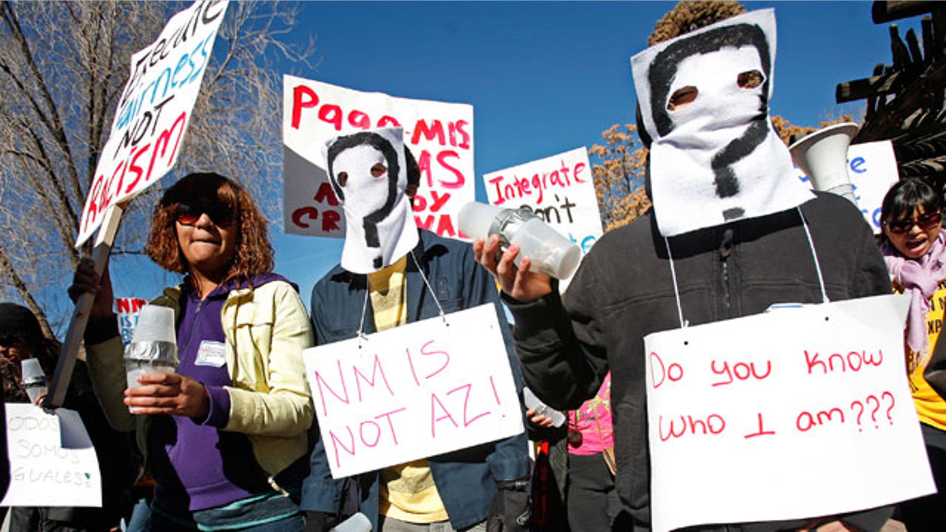 From right, Irvin Pacheco and Isiah Becerra wear masks and join protesters at the Capitol on Monday, Feb. 7, 2011 in Santa Fe. (AP)