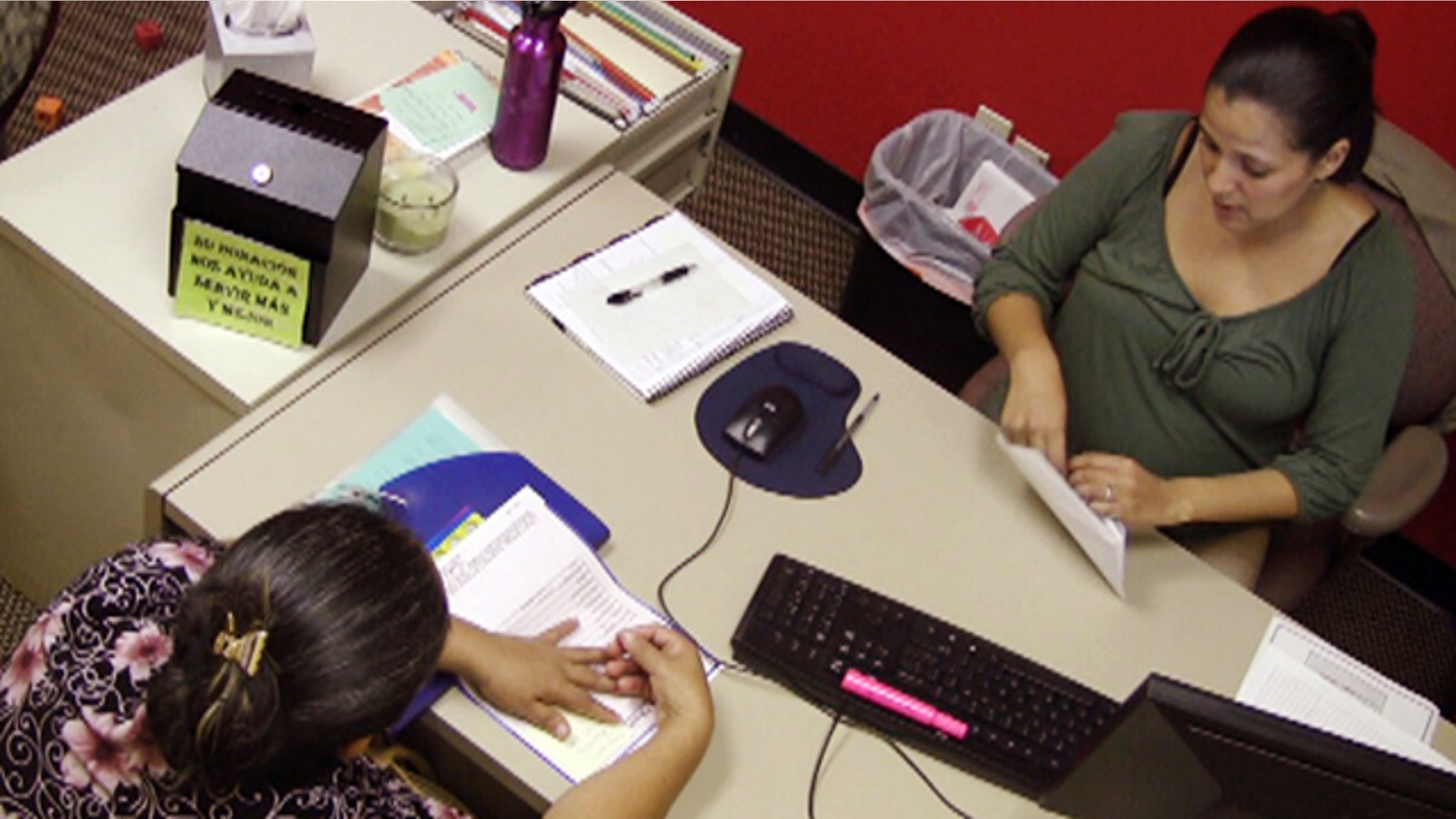 Oct. 6: In this photo taken from video, Jazmin Rivera, right, a case manager with the Hispanic Interest Coalition of Alabama, works with an unidentified immigrant in her office in Birmingham, Ala.