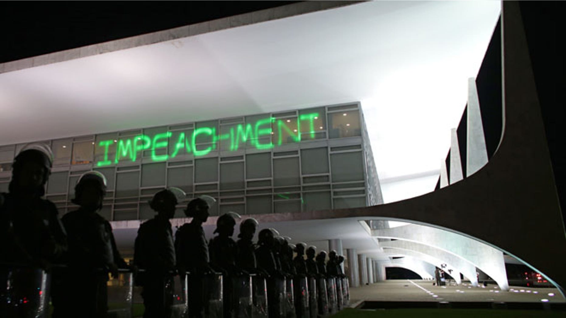 FILE - In this March 21, 2016 file photo, soldiers stand guard outside Planalto presidential palace where protesters projected the word "Impeachment" on the building, as they call for the impeachment of Brazil's President Dilma Rousseff in Brasilia, Brazil. On Thursday, the Senate will begin the final phase of Rousseff's trial for allegedly breaking fiscal rules in her management of the federal budget. Several days of deliberations, including an address by Rousseff herself, will culminate in a final vote early next week. (AP Photo/Eraldo Peres, File)
