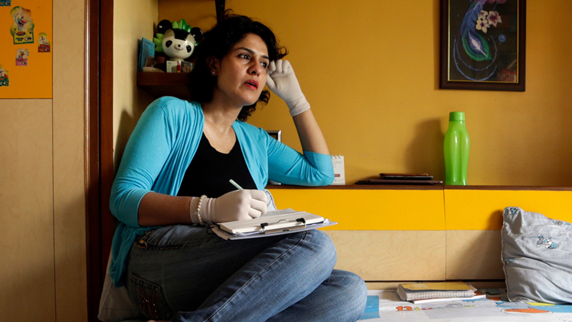 In this Friday, March 17, 2017 photo, Nidhi Chaphekar, Jet Airways flight attendant and a victim of the Brussels airport terror attack, pens down her thoughts at her residence in Mumbai, India. Chaphekar, 40, mother of two from Mumbai is one of the survivors of the last year's Brussels airport terror attack in which at least 30 people were killed and more than 200 wounded. Chaphekar said she has recovered 70 percent of her previous fitness level and would like to resume her passion, flying. (AP Photo/Rajanish Kakade)