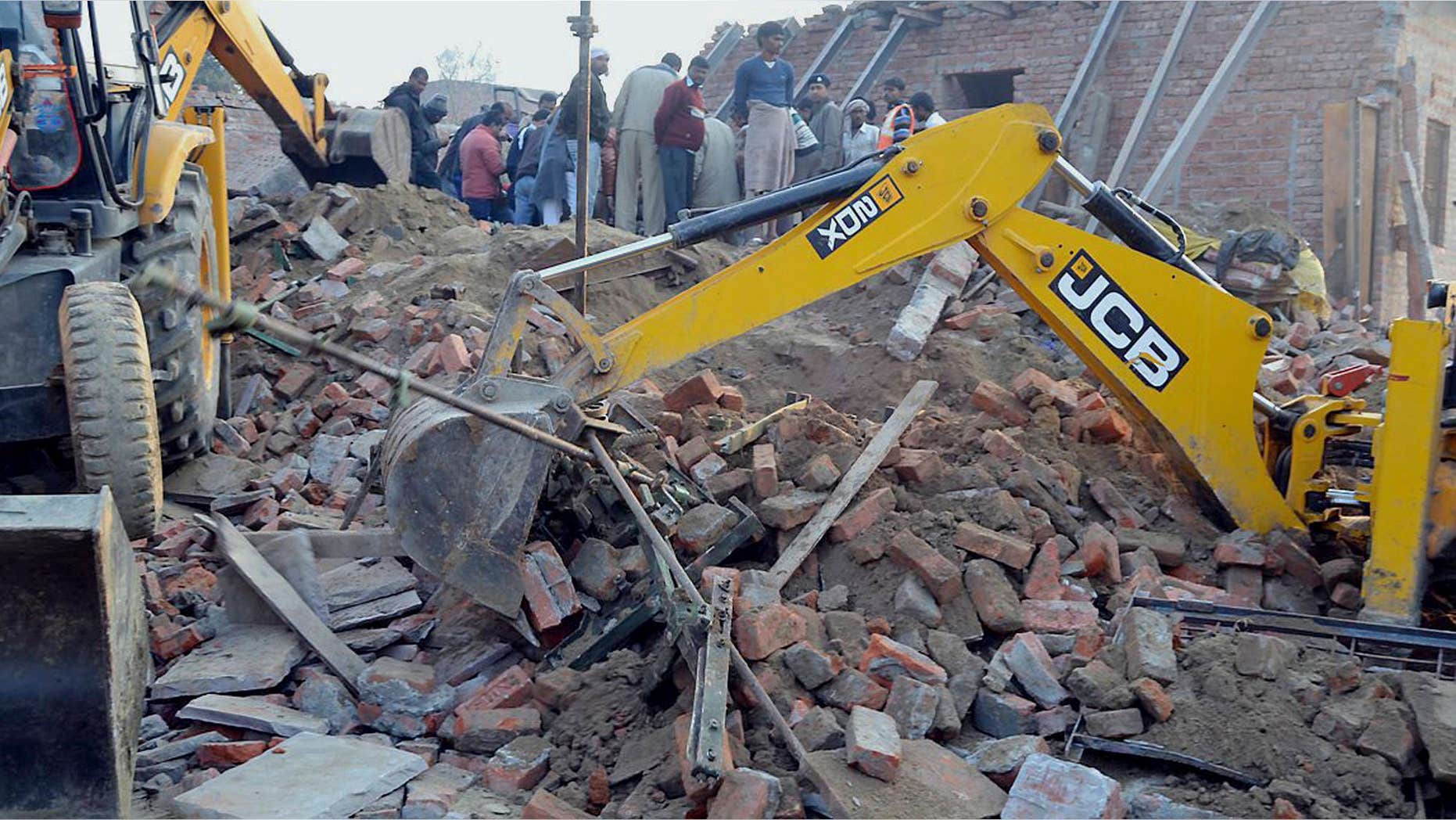 Feb. 15, 2015: Rescuers use machinery to remove the debris after a building that was under construction collapsed overnight, in the town of Mughalsarai.