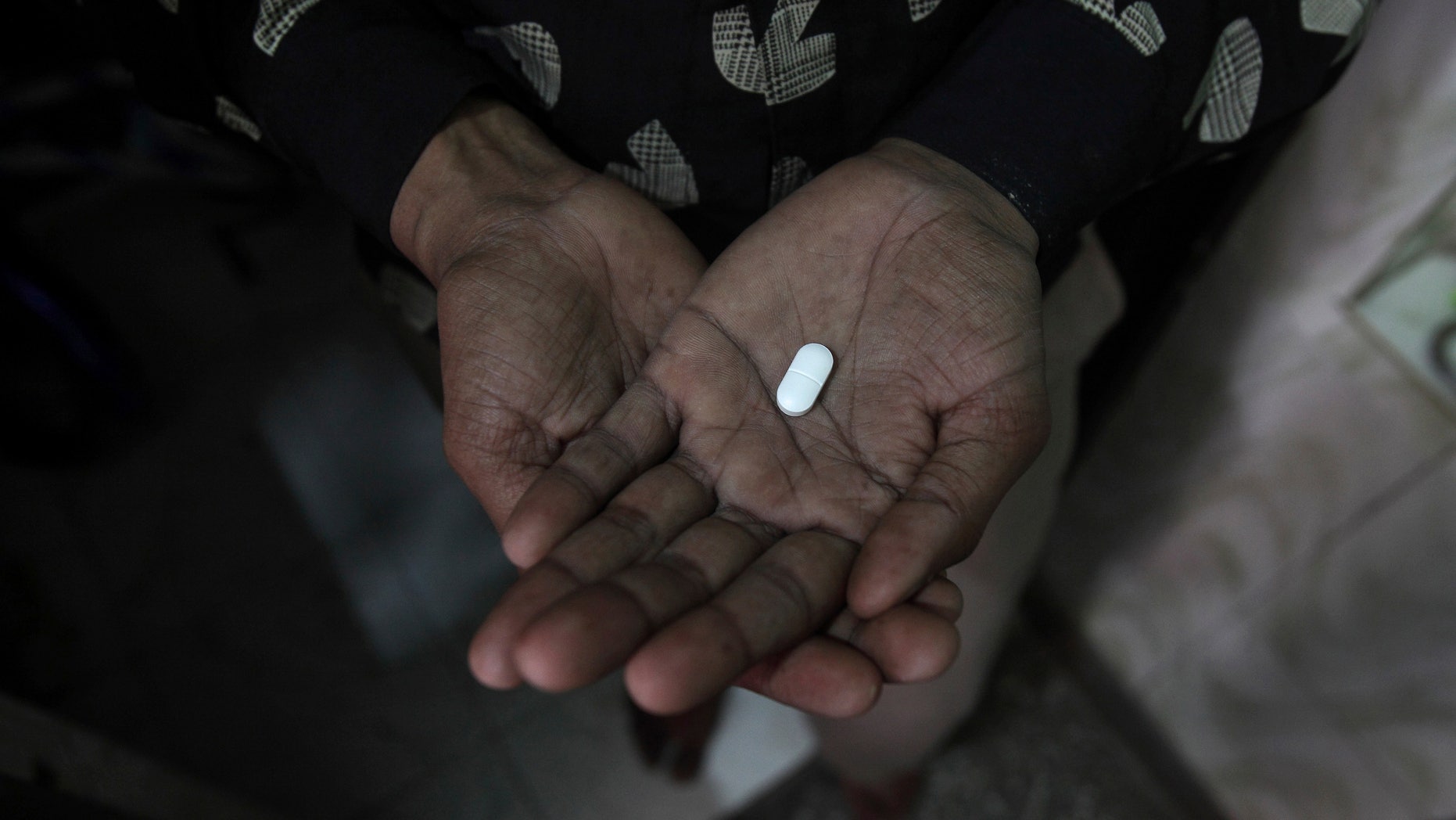 Seema (R), 33, displays an anti-retroviral drug used to treat HIV/AIDS, inside his residence in New Delhi. REUTERS/Adnan Abidi