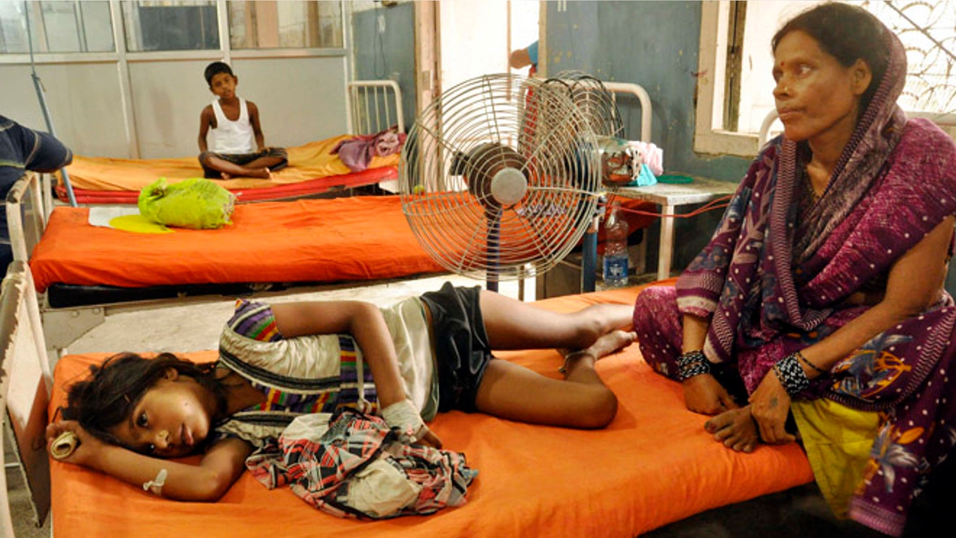 July 18, 2013: An Indian woman sits beside a child who fell sick after eating a free school lunch, at a hospital in Patna, India. Indian officials say at least 22 children have died and more than two dozen others were sickened after eating a free school lunch that was tainted with insecticide.
