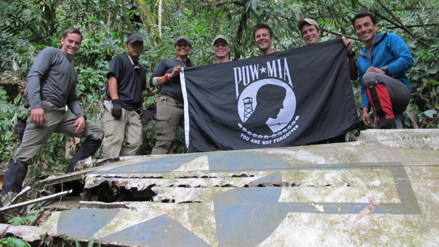 Members from Defense POW/MIA Accounting Agency (DPAA), hold the POW/MIA flag above a piece of metallic debris during a DPAA investigation mission near Bhismaknagar Village, Arunachal Pradesh, India, Dec. 02, 2016. (DoD photo by U.S. Marine Staff Sgt. Christopher Cantu)