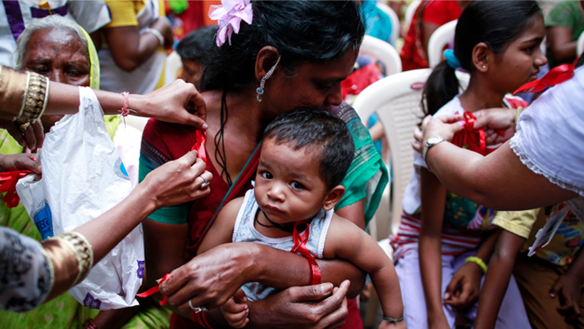 Dec. 1, 2014: A volunteer pins a red ribbon on the blouse of a sex worker, as her child looks on, during an event to mark World AIDS Day in Kamathipura, Mumbai's red light district.