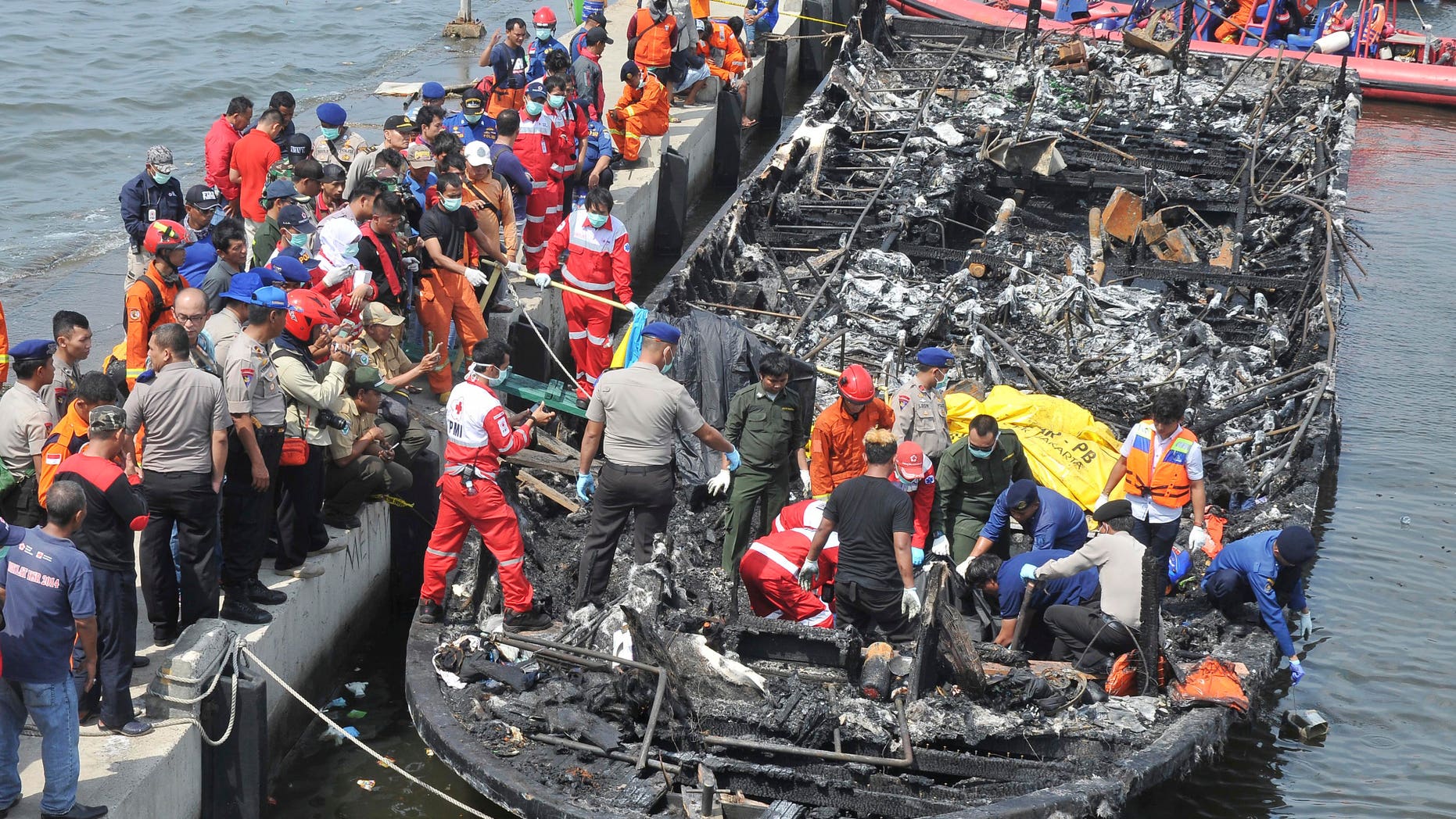 Rescuers search for victims from the wreckage of a ferry that caught fire off the coast of Jakarta after it was docked at Muara Angke Port in Jakarta, Indonesia, Sunday, Jan. 1, 2017. The vessel was carrying more than 230 people from the port to Tidung, a resort island in the Kepulauan Seribu chain, when it caught fire, officials said. (AP Photo/Rhana Ananda)