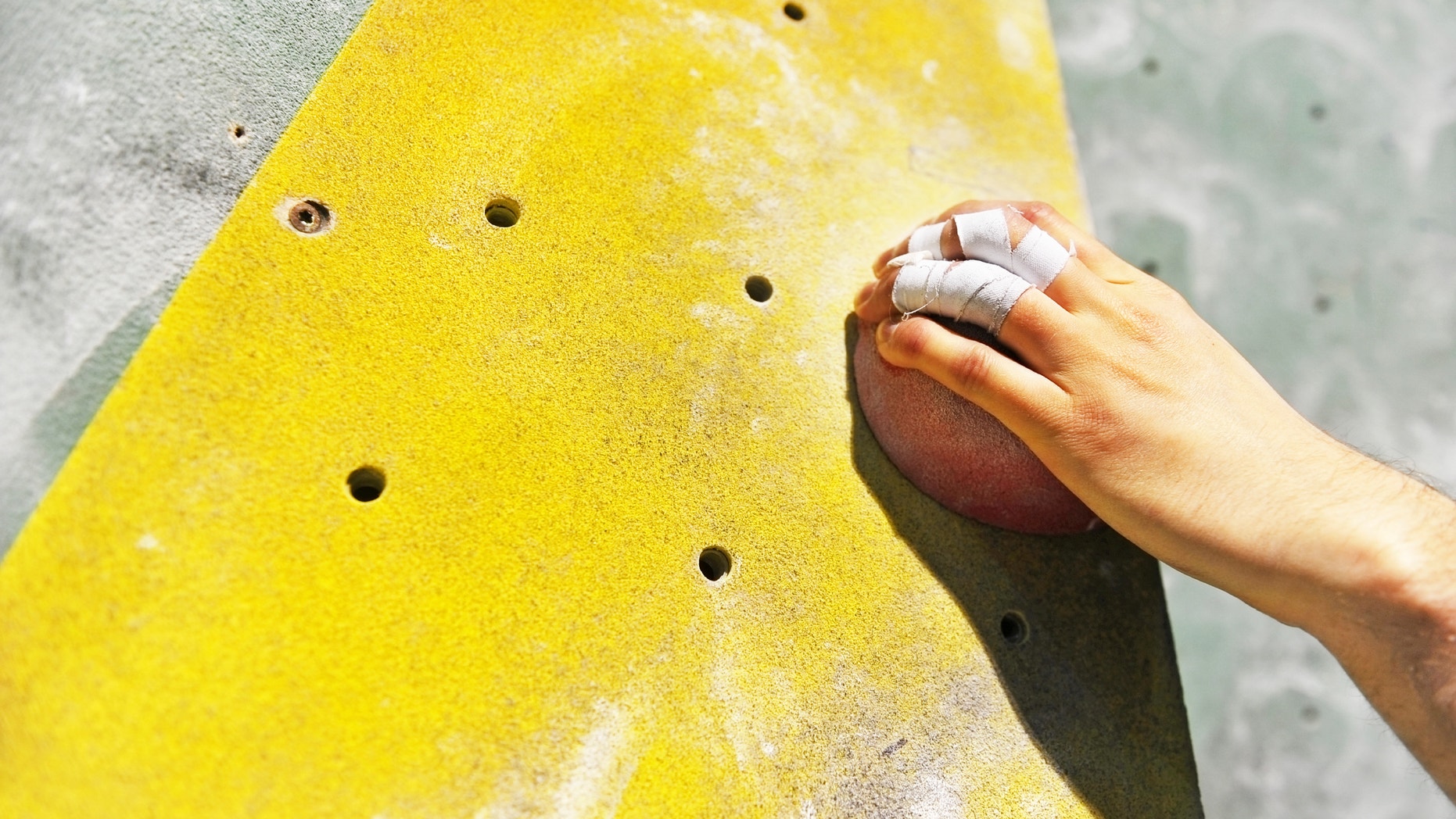 Detail with climber hand on artificial indoor climbing wall